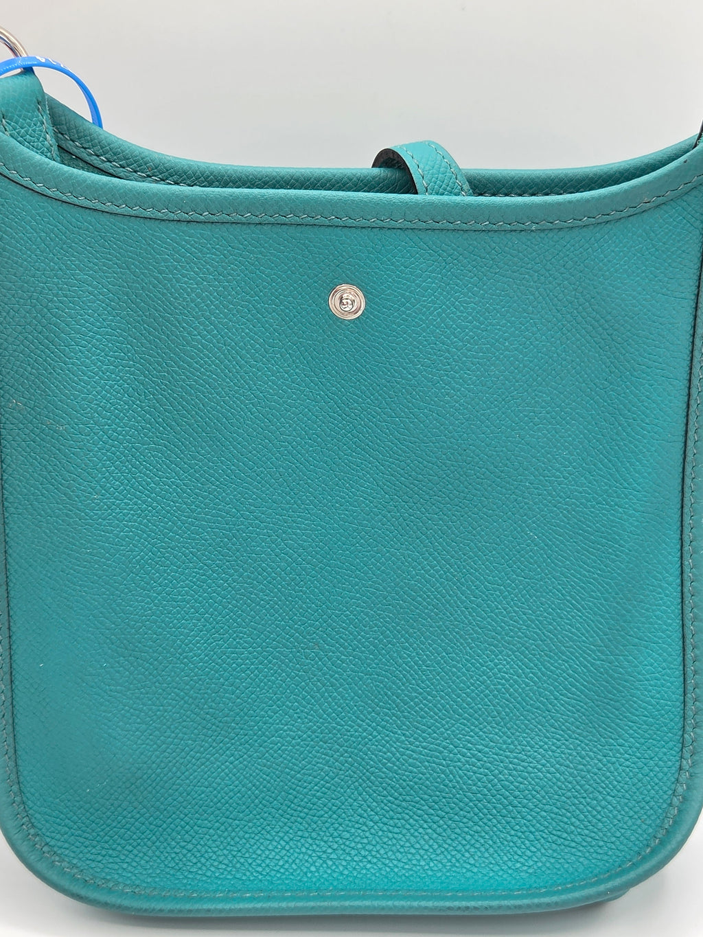 Teal leather bag with a visible brand logo on a light gray background