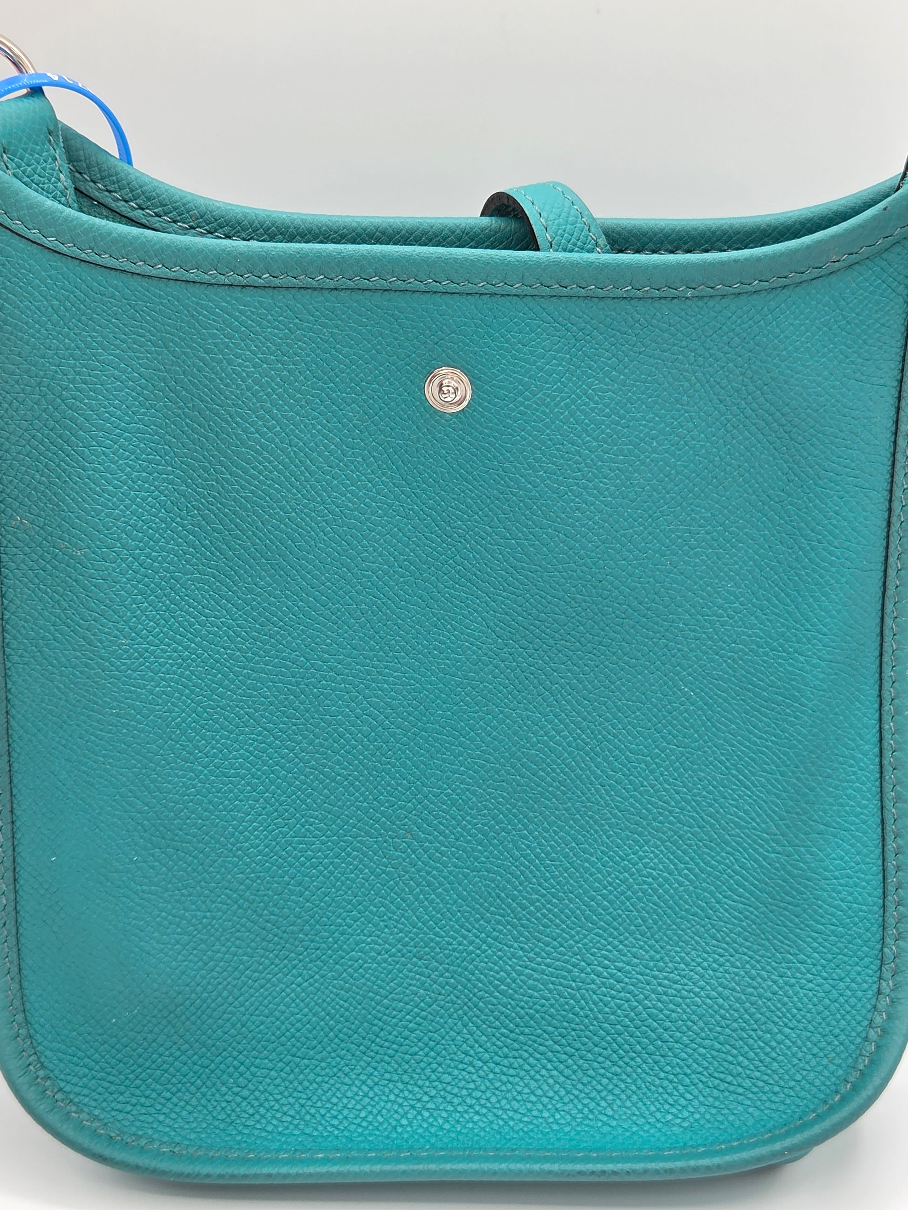 Teal leather bag with a visible brand logo on a light gray background