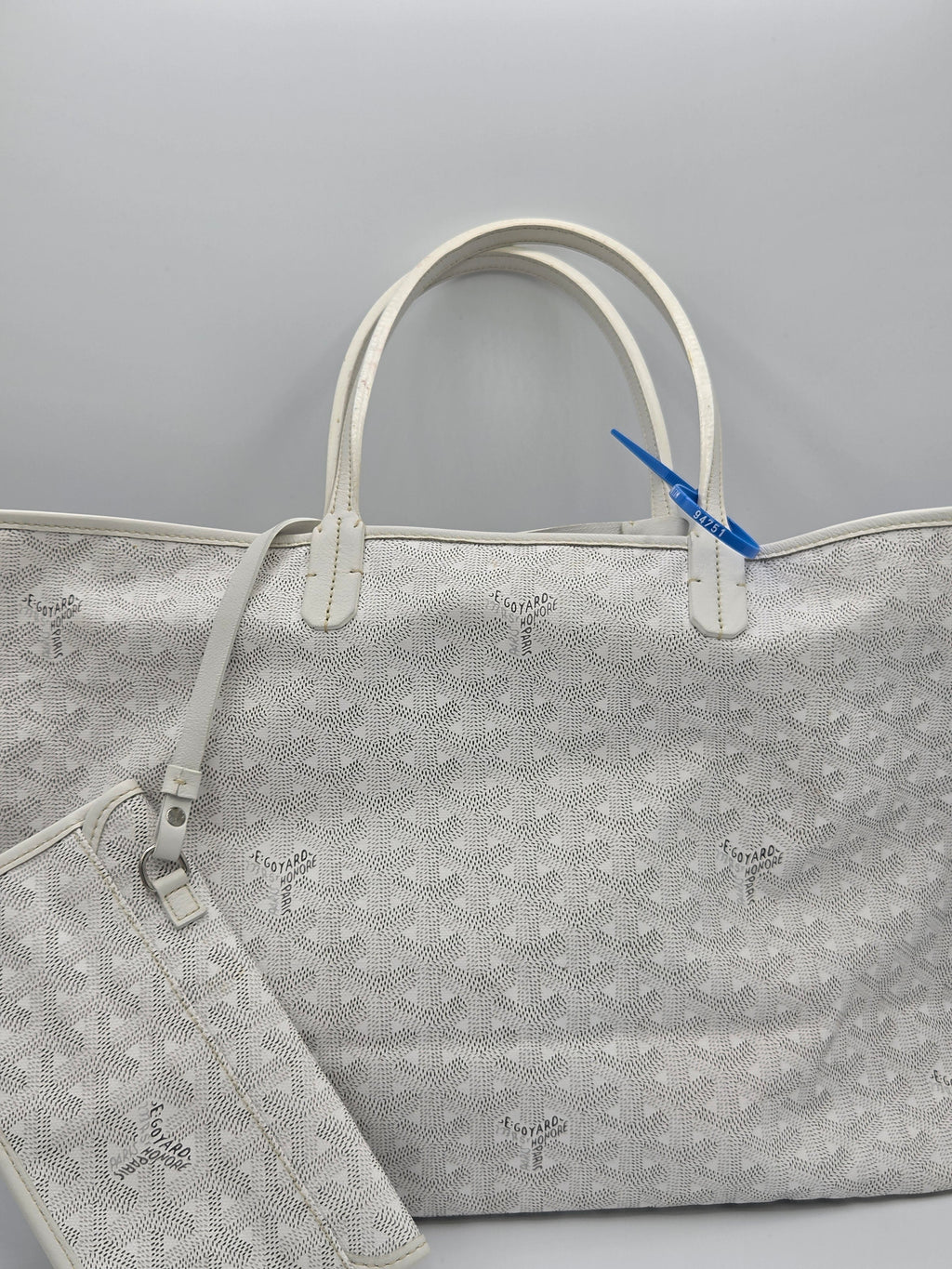 Gray patterned bag with a blue tag on a light gray background