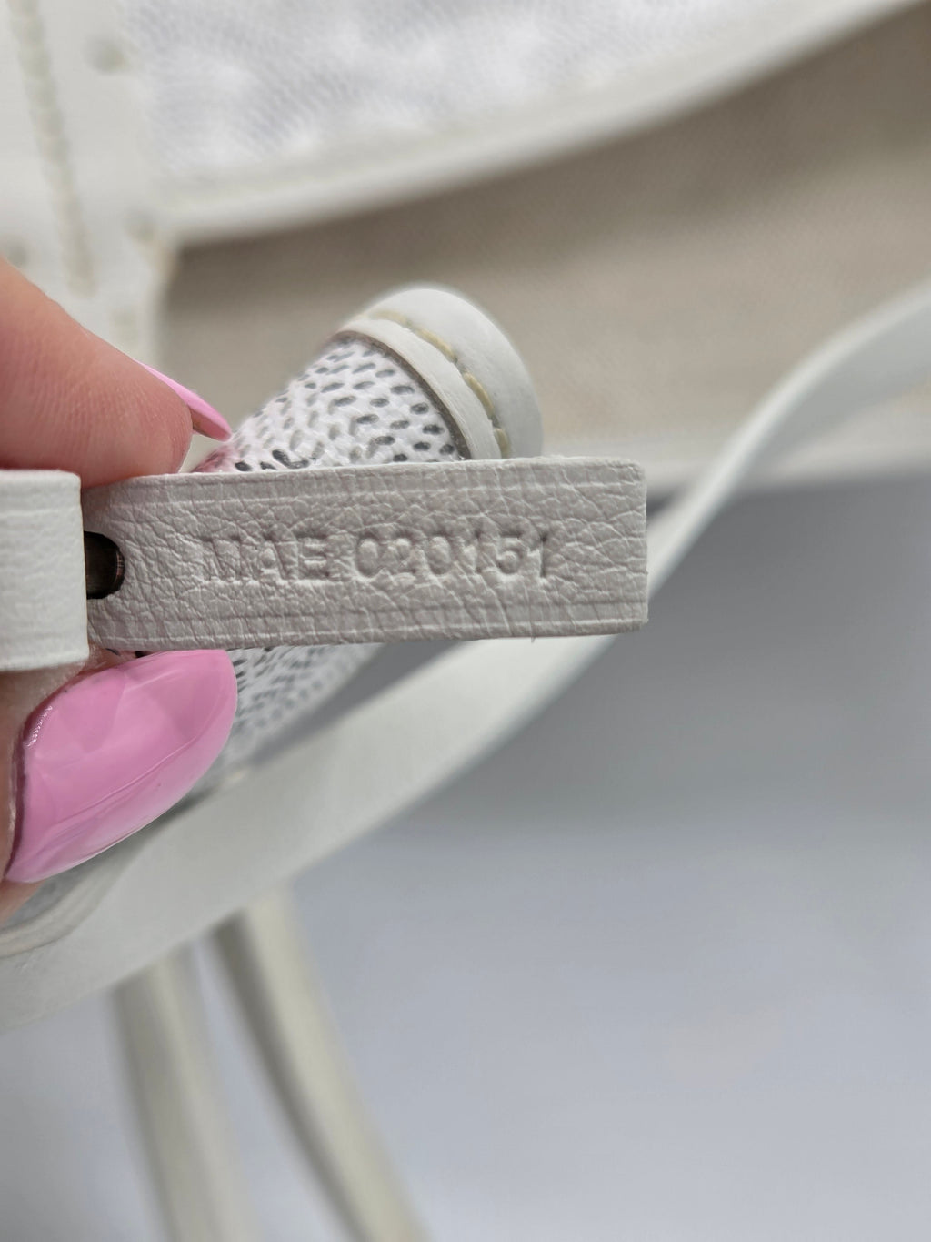 Close-up of a white sneaker with 'Puma' branding held by a hand.