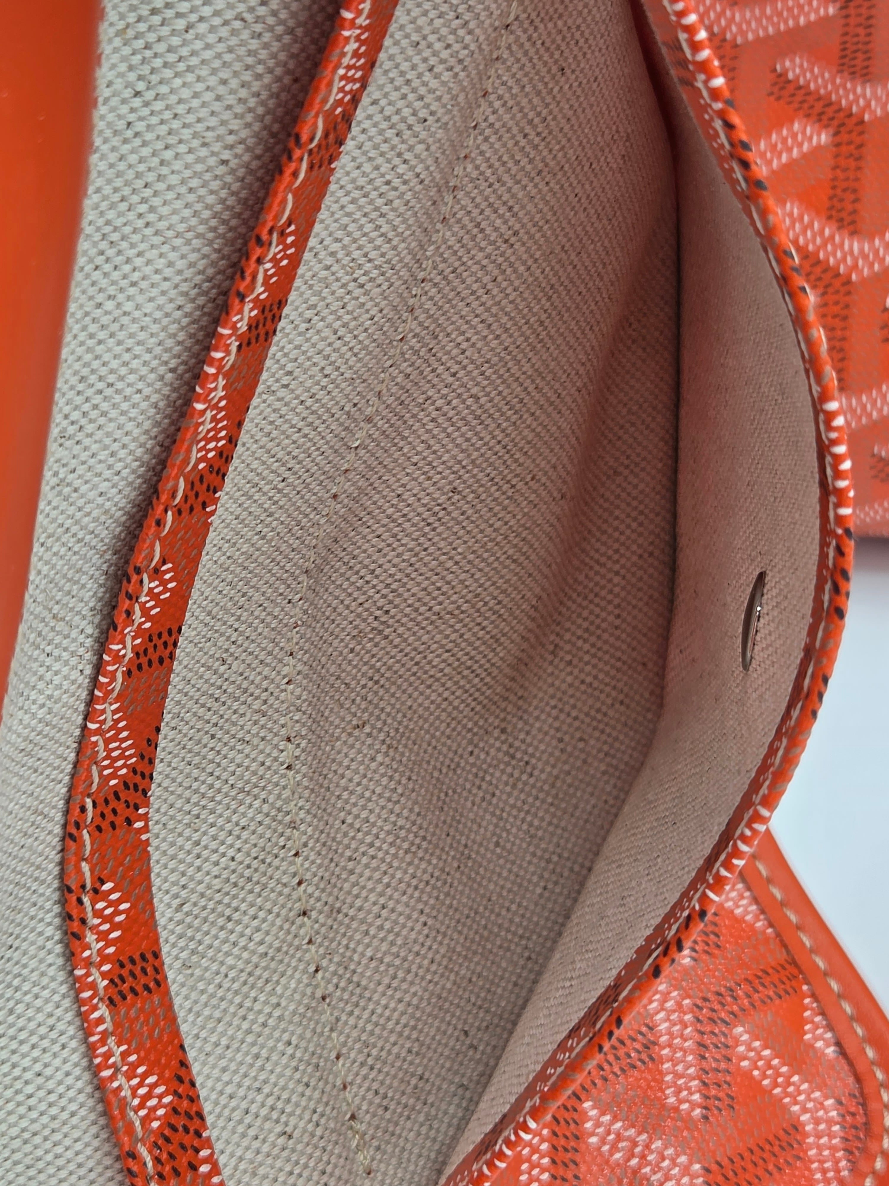 Close-up of a brown leather bag with intricate stitching on a light gray background