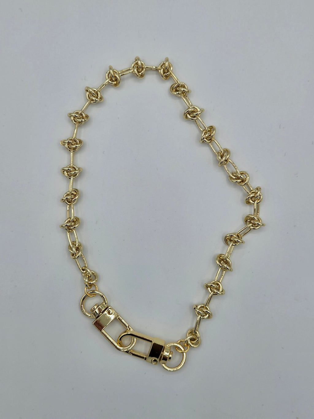 Gold chain bracelet on a light gray background