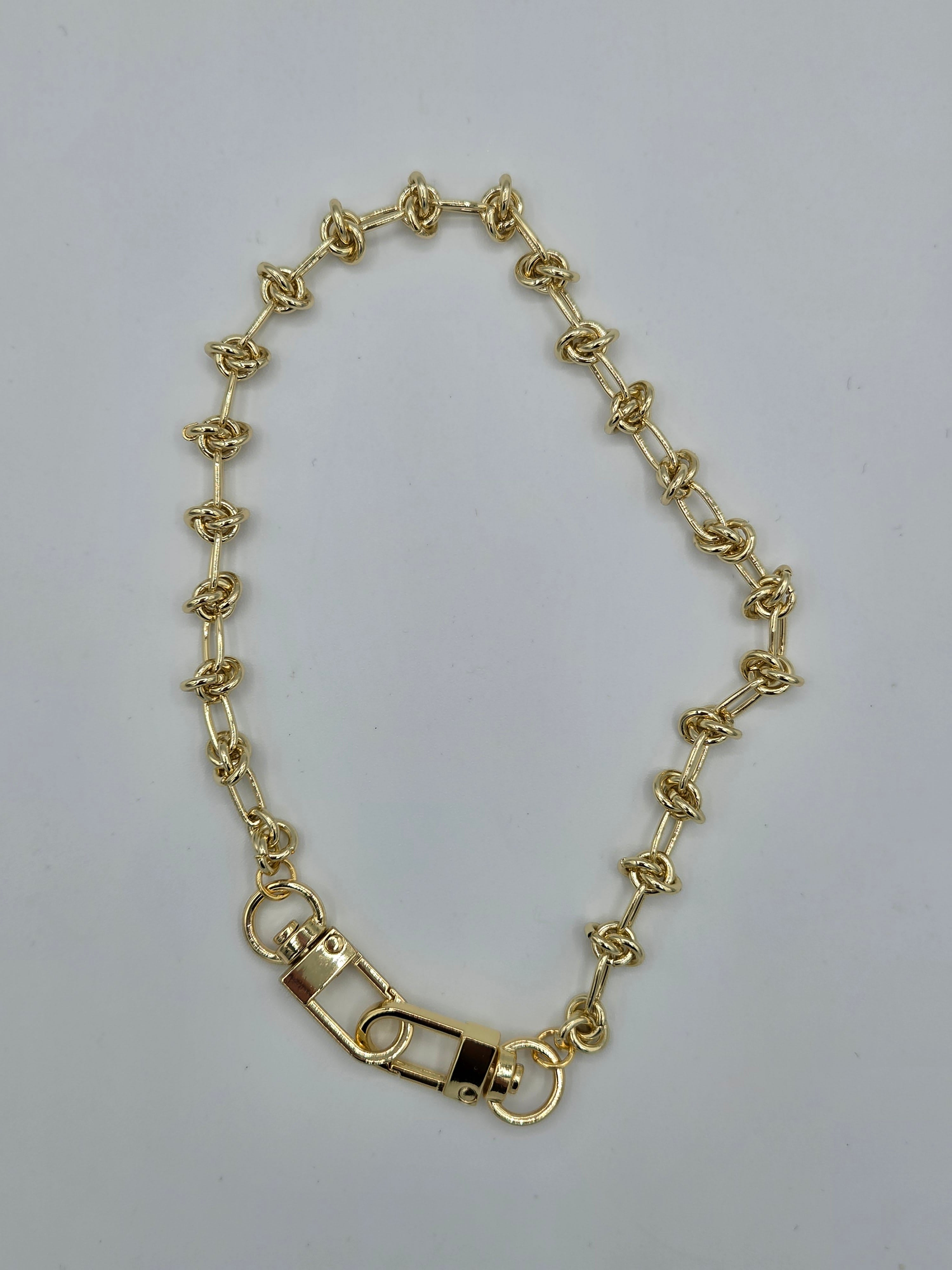 Gold chain bracelet on a light gray background