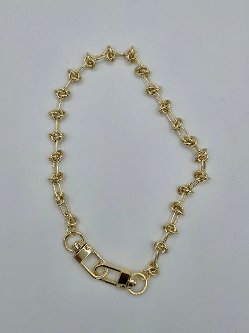 Gold chain bracelet on a light gray background