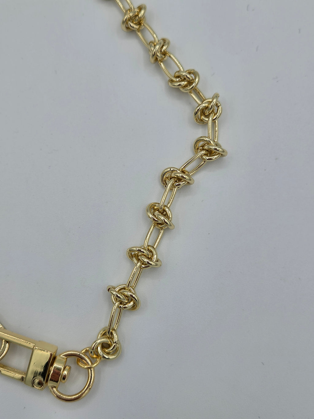 Gold chain bracelet on a light gray background