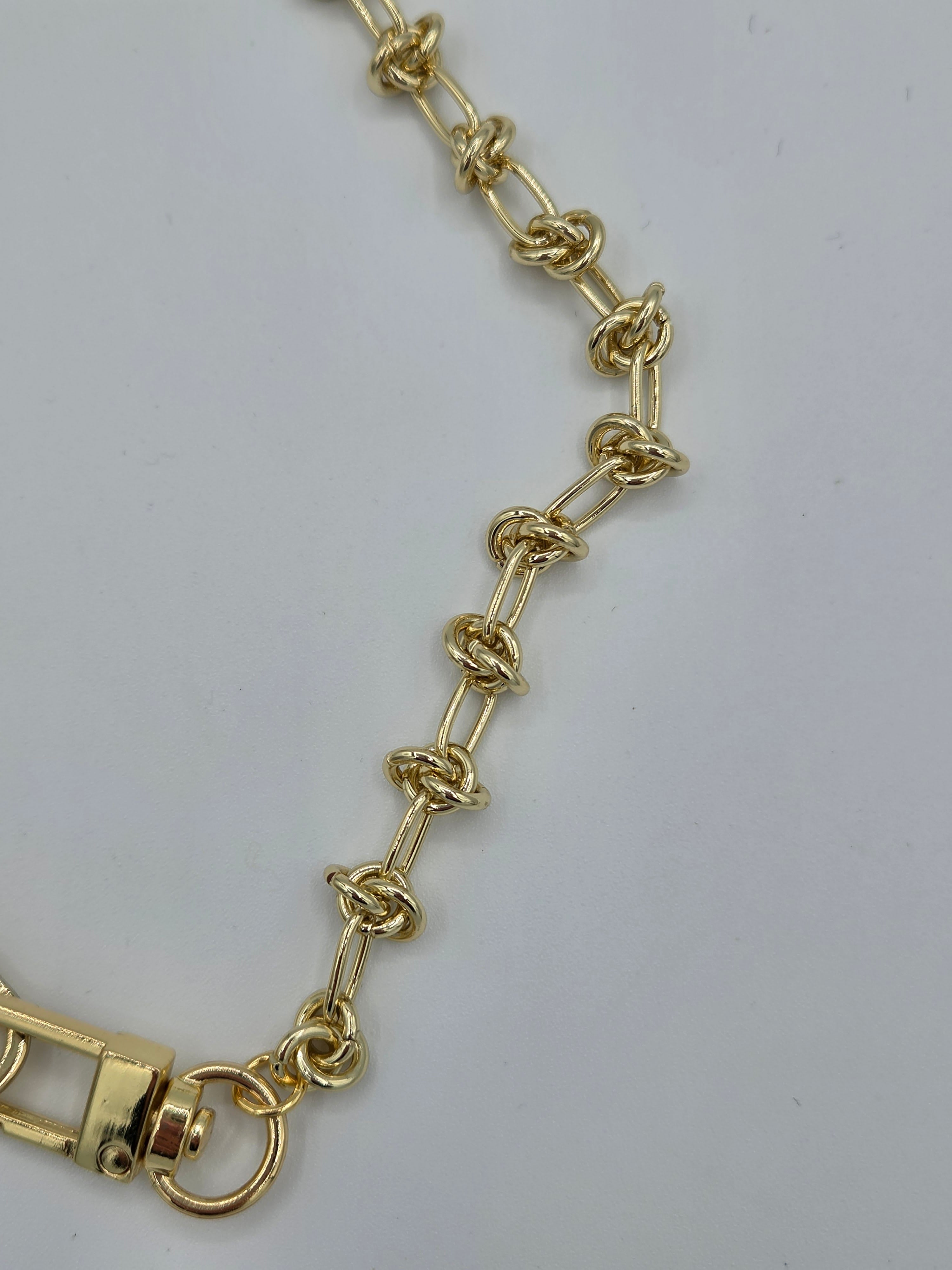 Gold chain bracelet on a light gray background