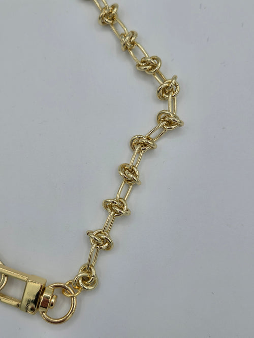 Gold chain bracelet on a light gray background