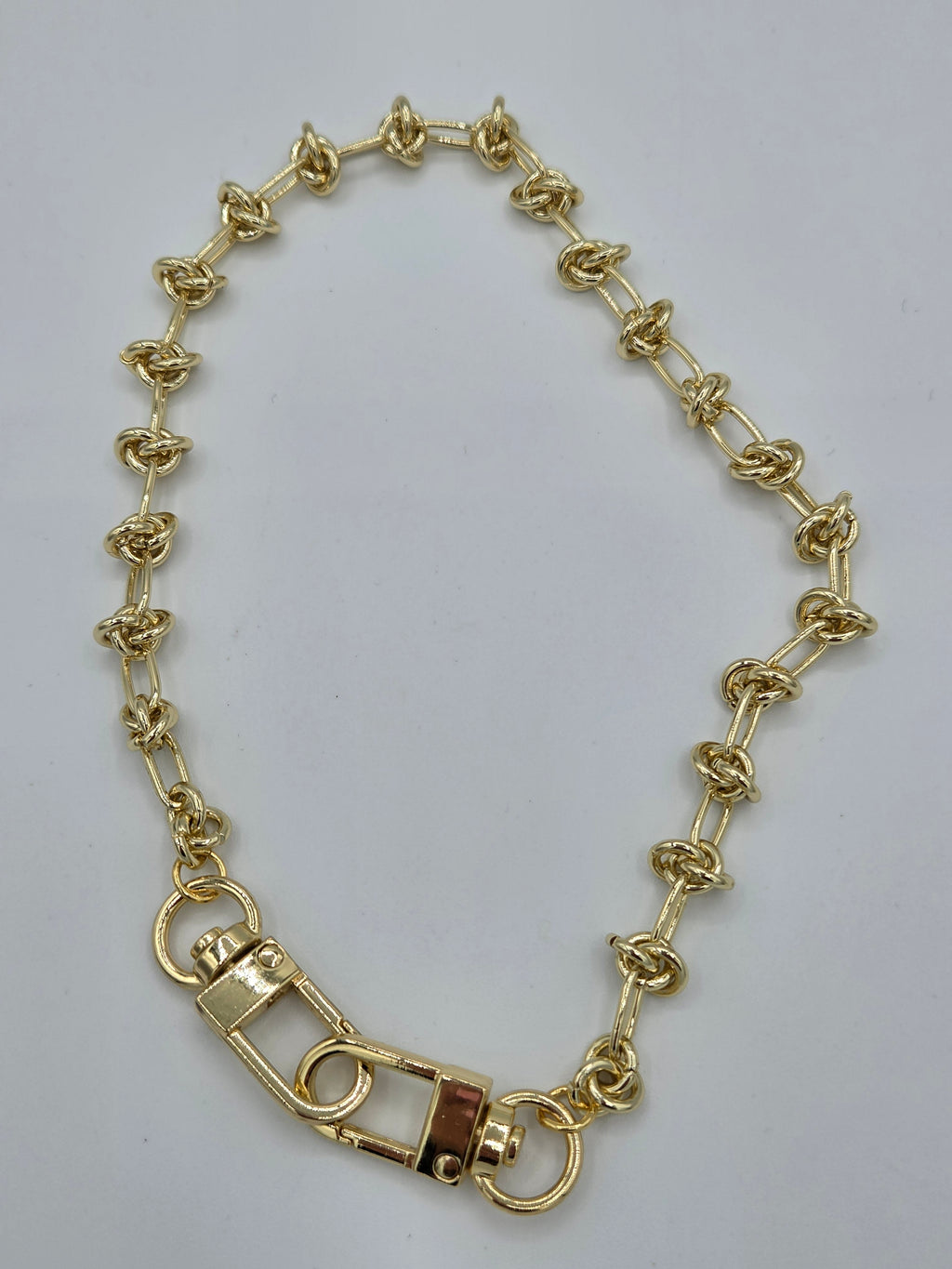 Gold chain bracelet on a light gray background