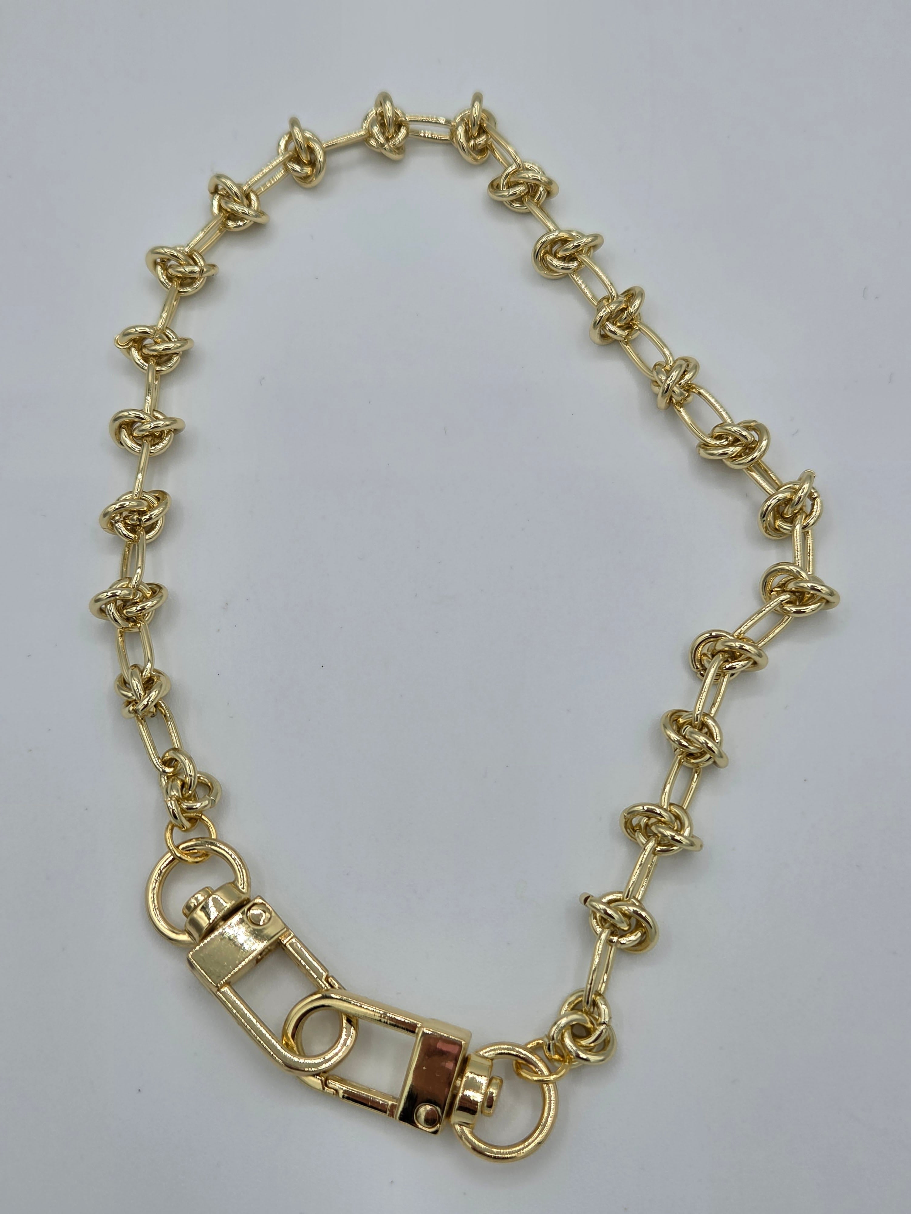 Gold chain bracelet on a light gray background
