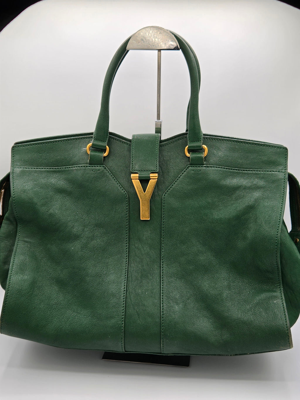 Green leather handbag with gold accents on a white background