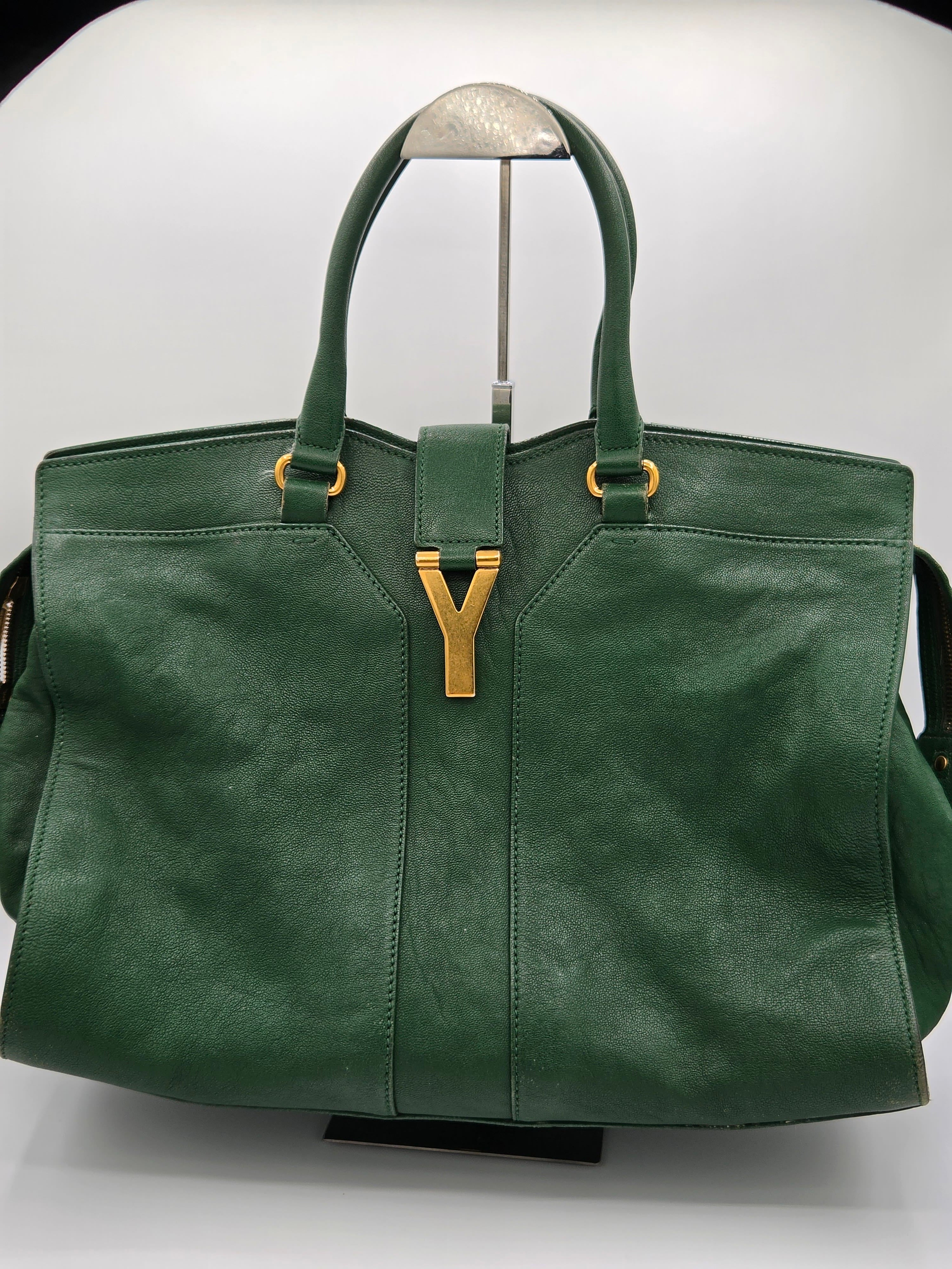 Green leather handbag with gold accents on a white background