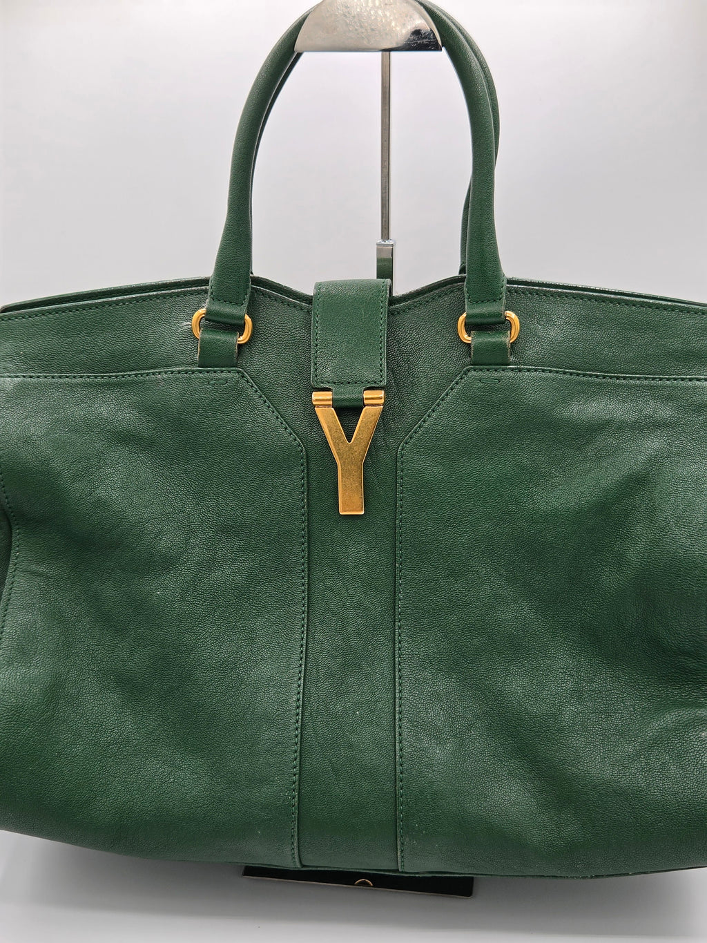 Green leather bag with gold Y-shaped clasp on a white background