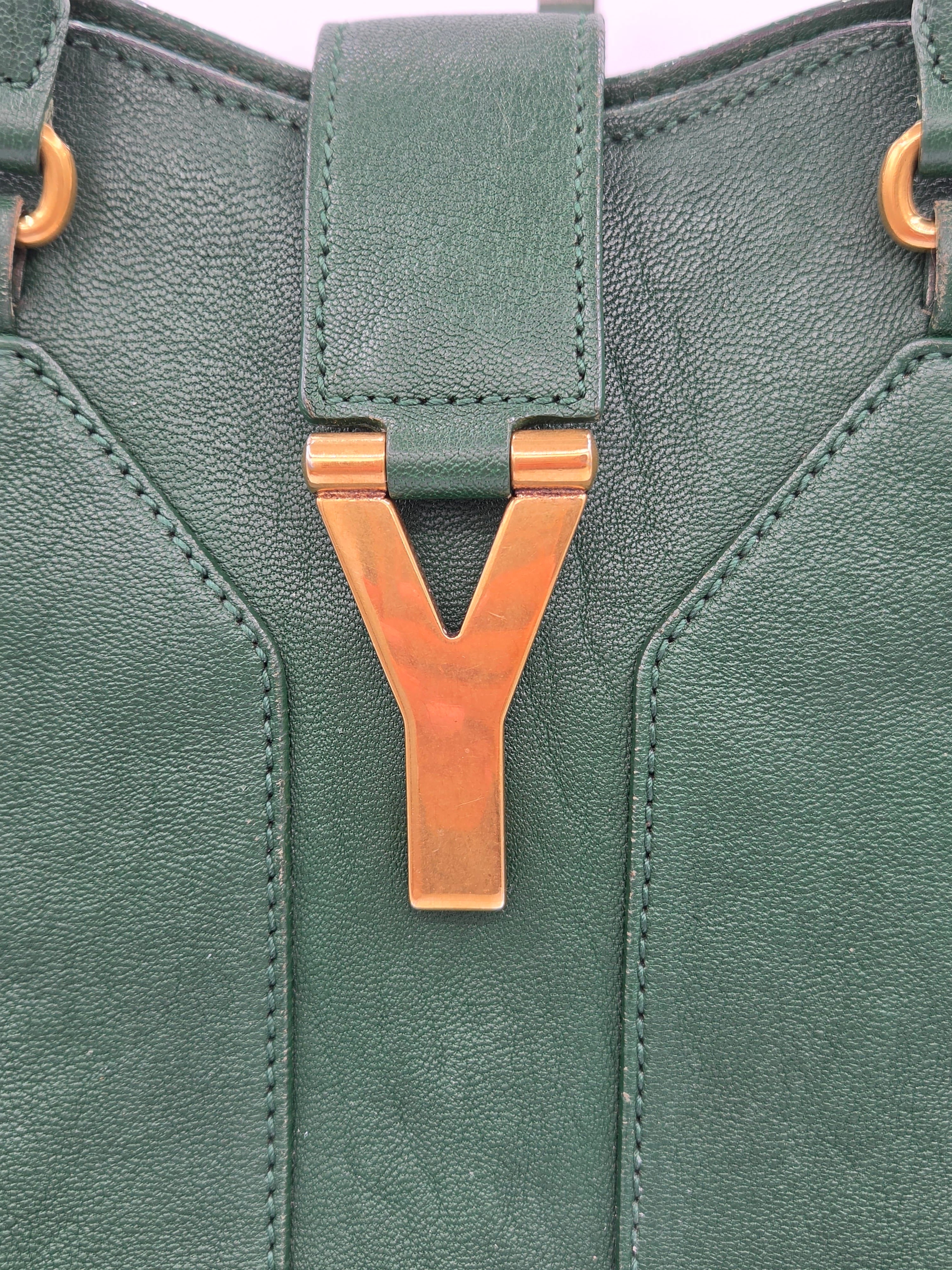 Green leather bag with a bronze buckle on a light purple background