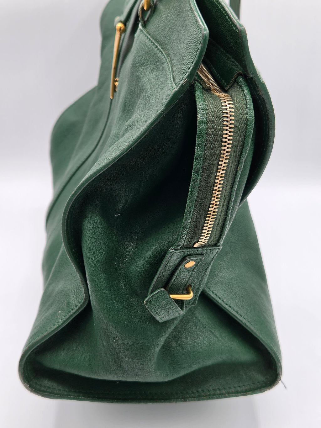 Green handbag with gold zippers on a white background