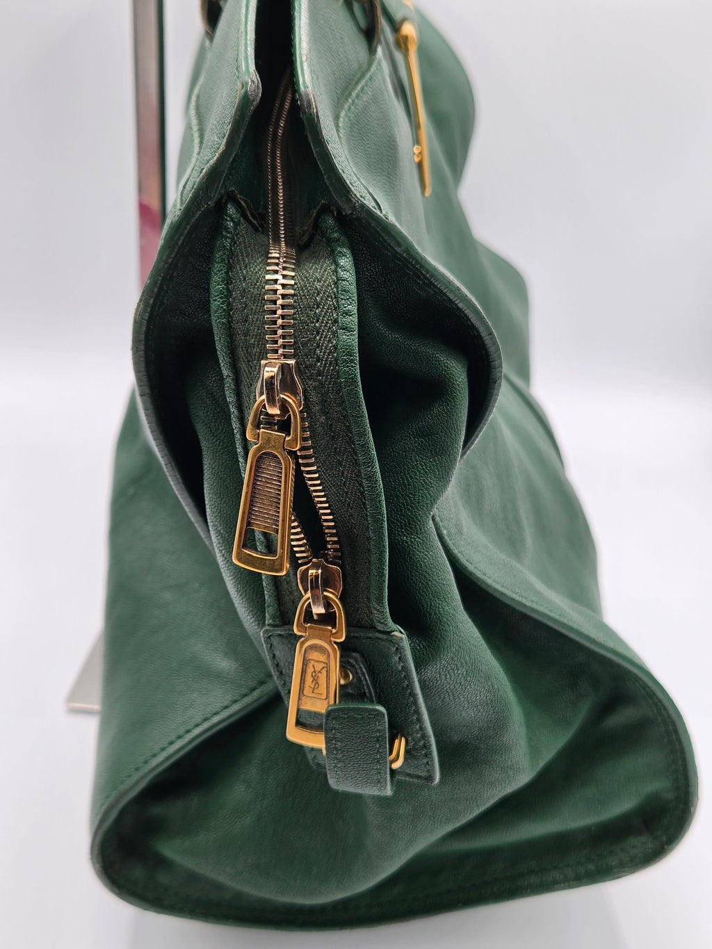 Green leather bag with gold zippers on a white background