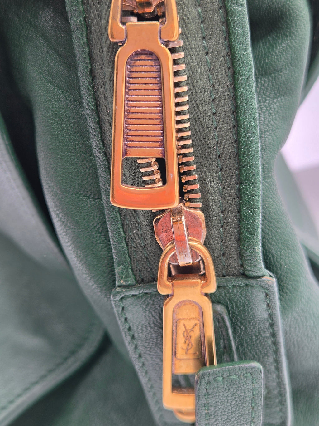 Close-up of a gold zipper on a green fabric background