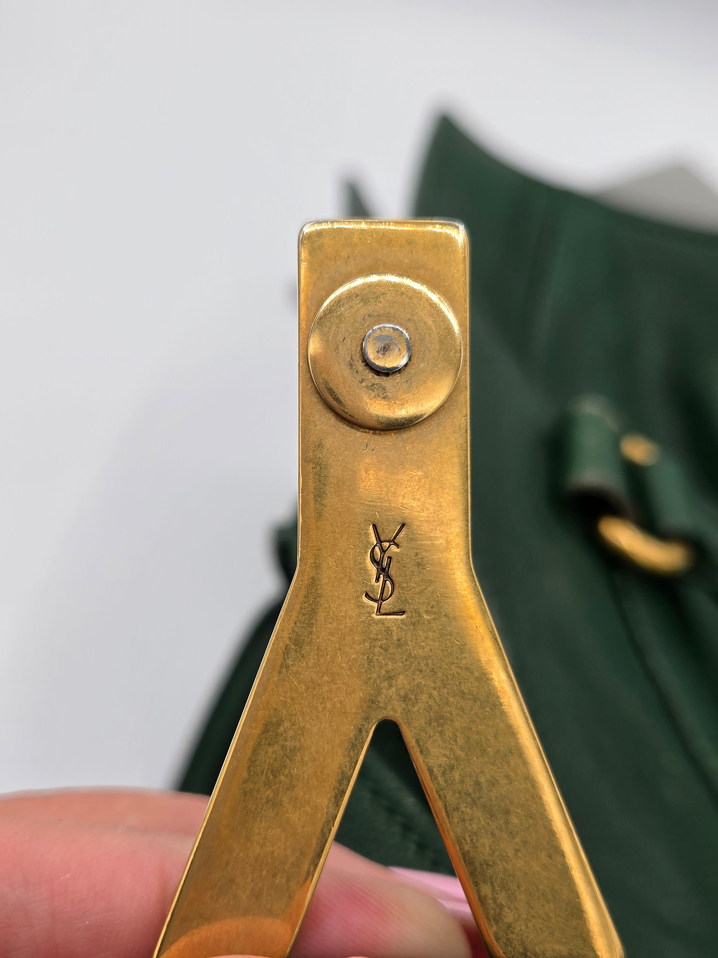 Gold tool with a brand logo held by a hand against a blurred green background
