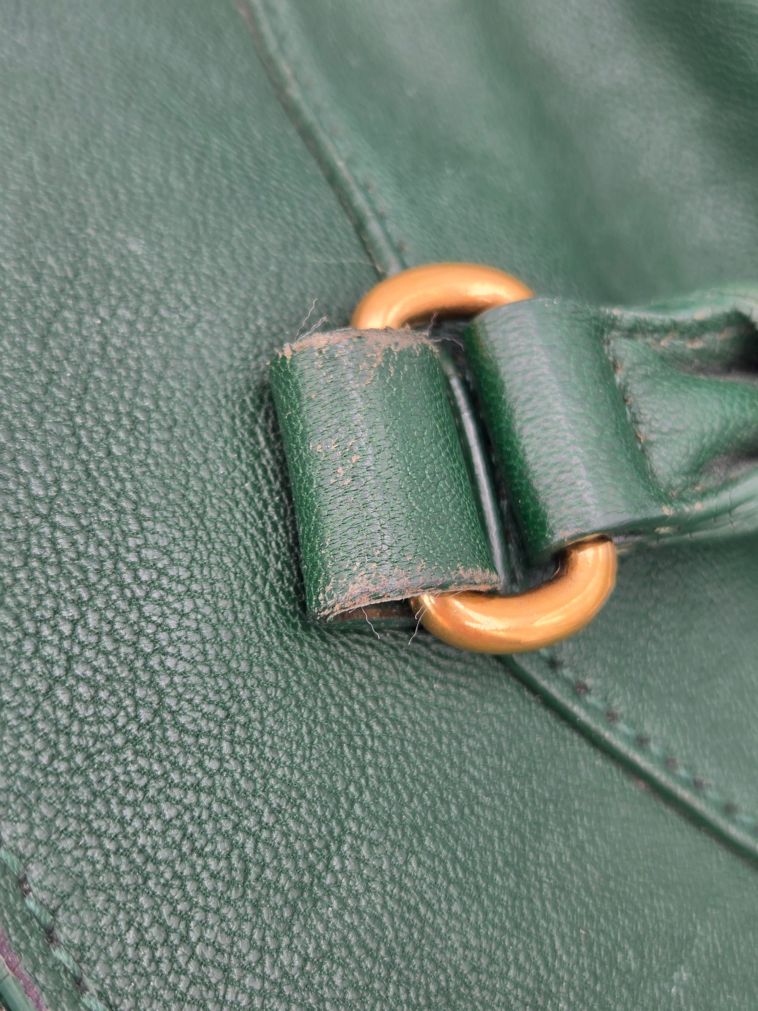 Close-up of a green leather bag with a gold buckle.