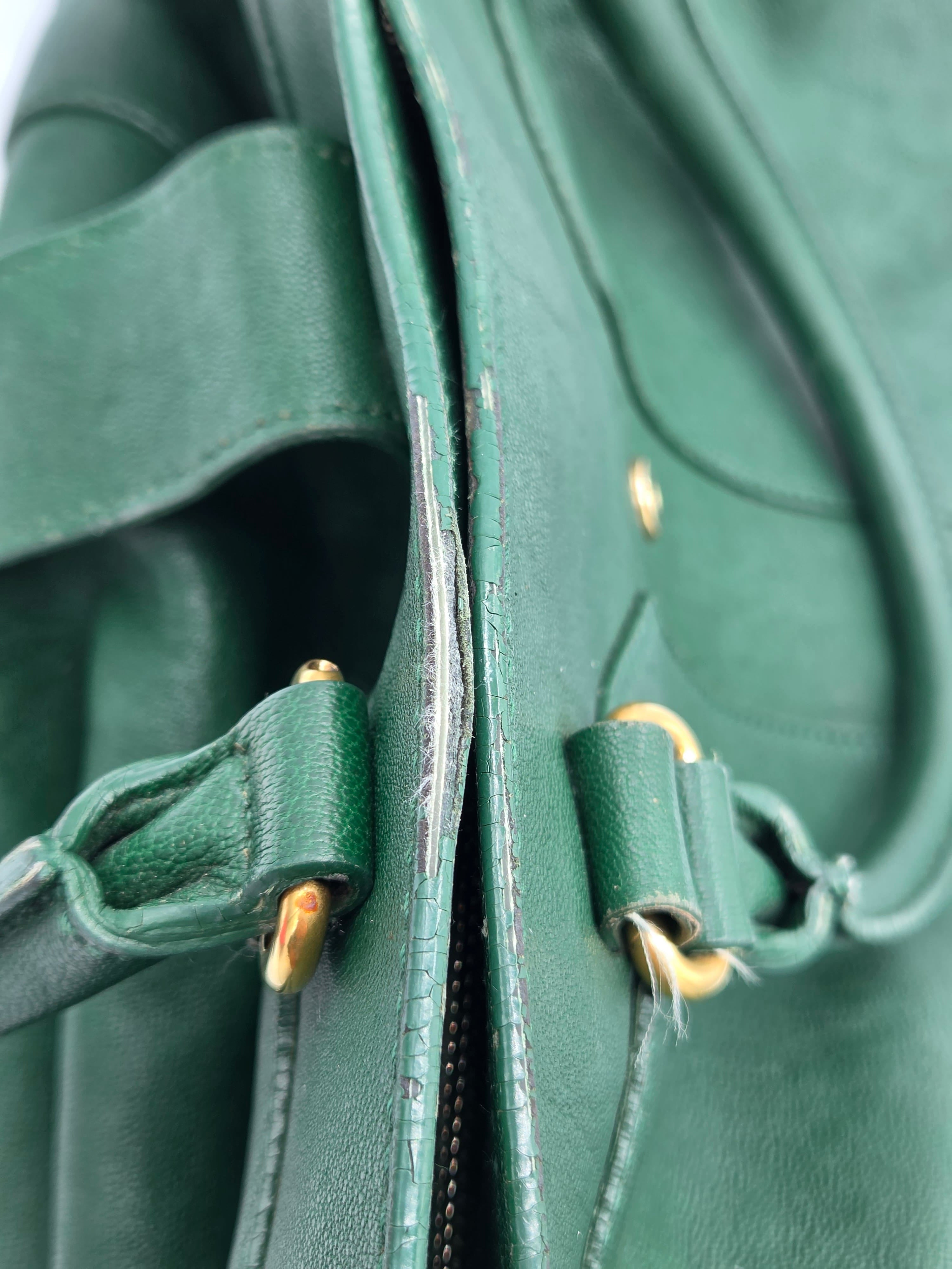 Close-up of a green leather bag with gold zipper pulls.