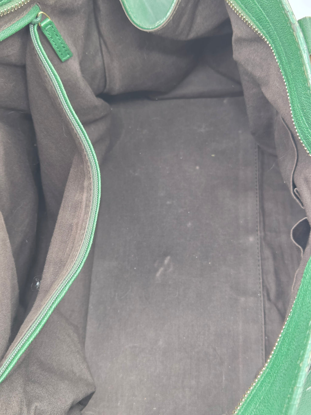 Close-up of a black bag with green zippers and trim.