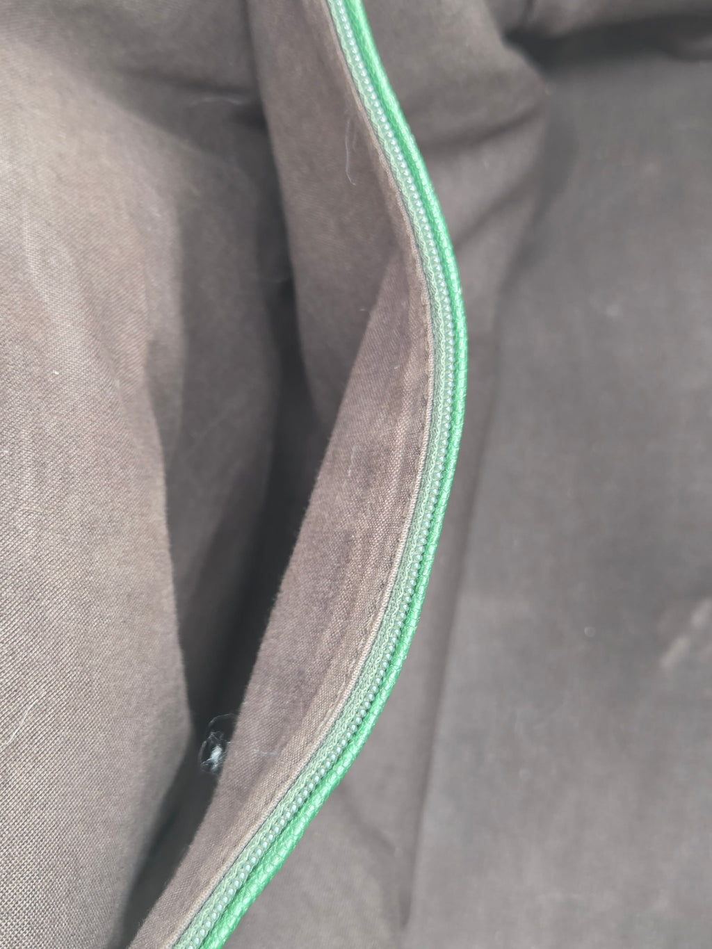 Close-up of gray fabric with a green zipper