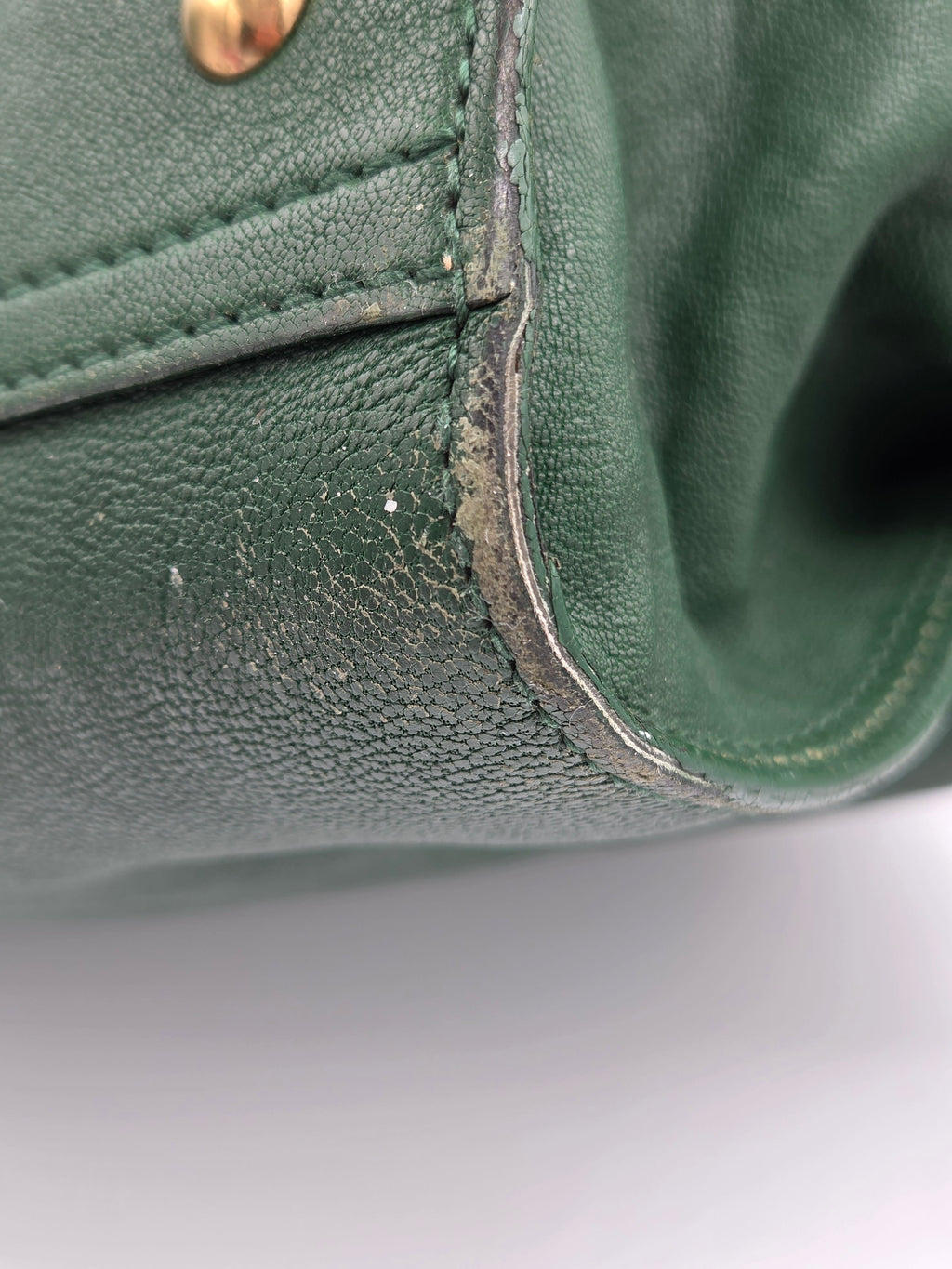 Close-up of a green leather product with visible wear and tear.