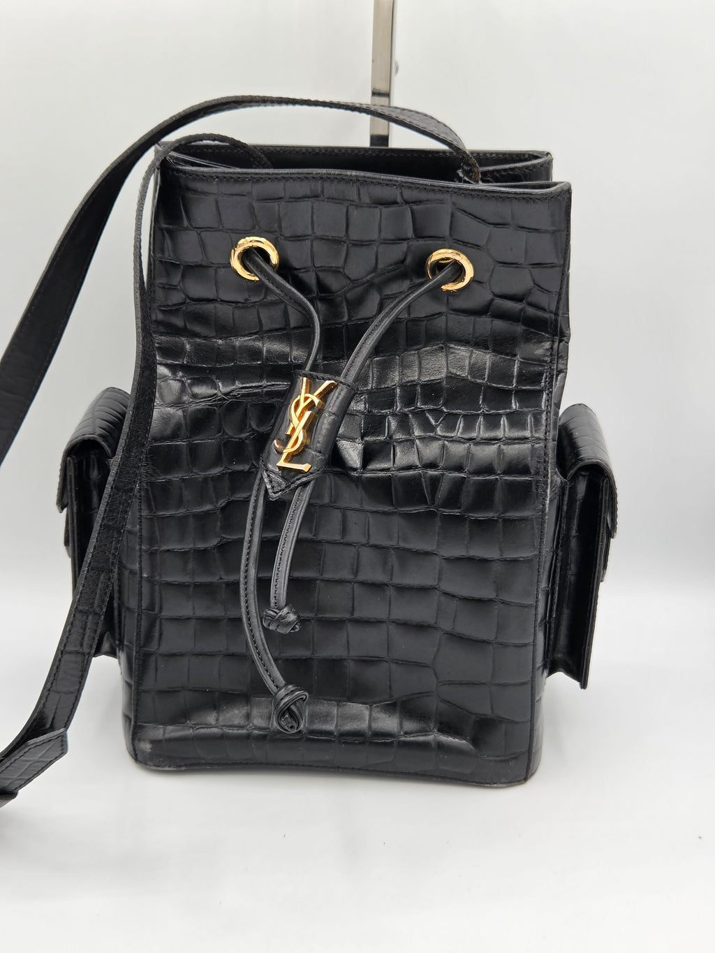 Black crocodile skin handbag with gold accents on a white background