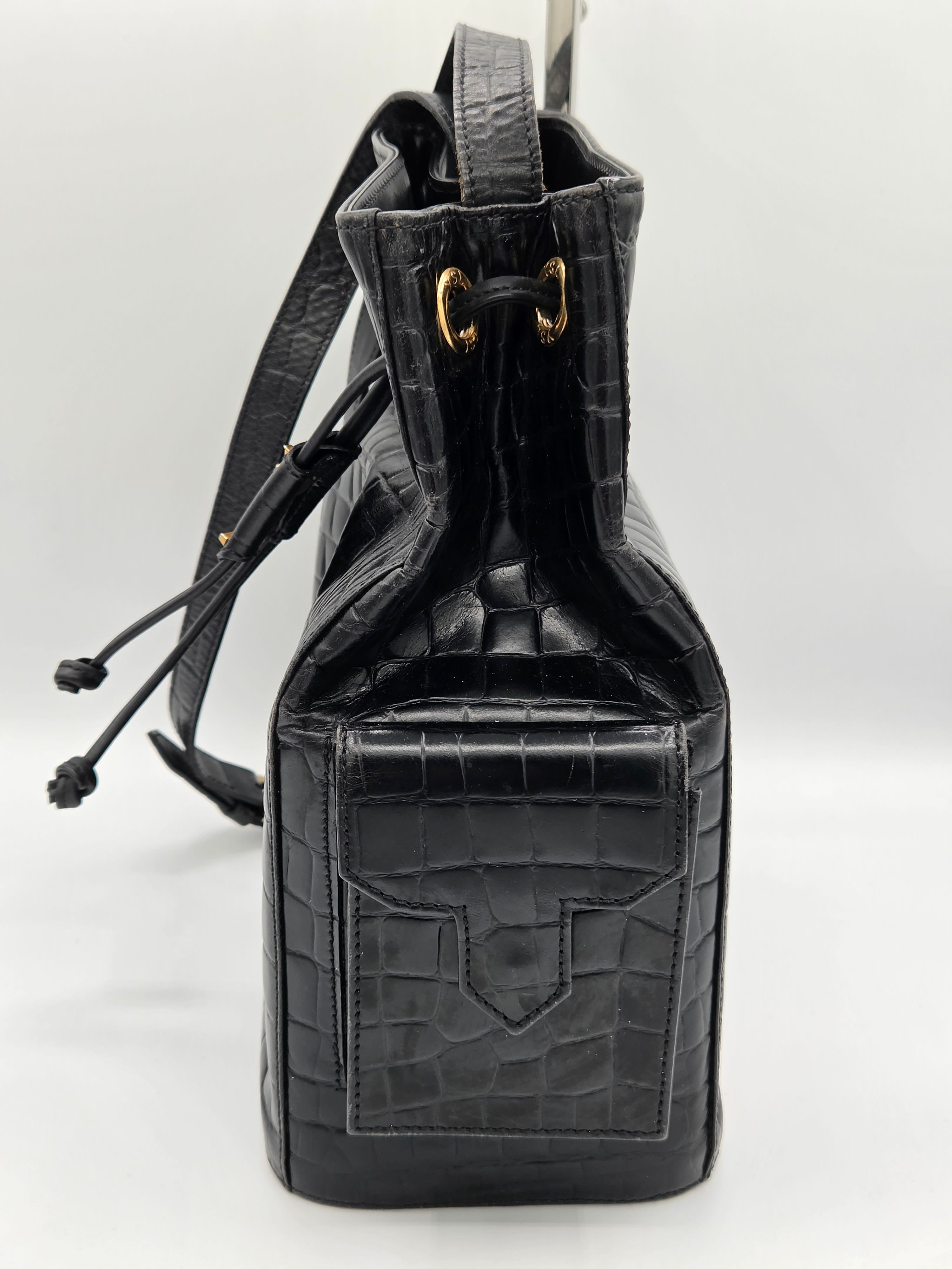 Black crocodile skin handbag with drawstring on a white background