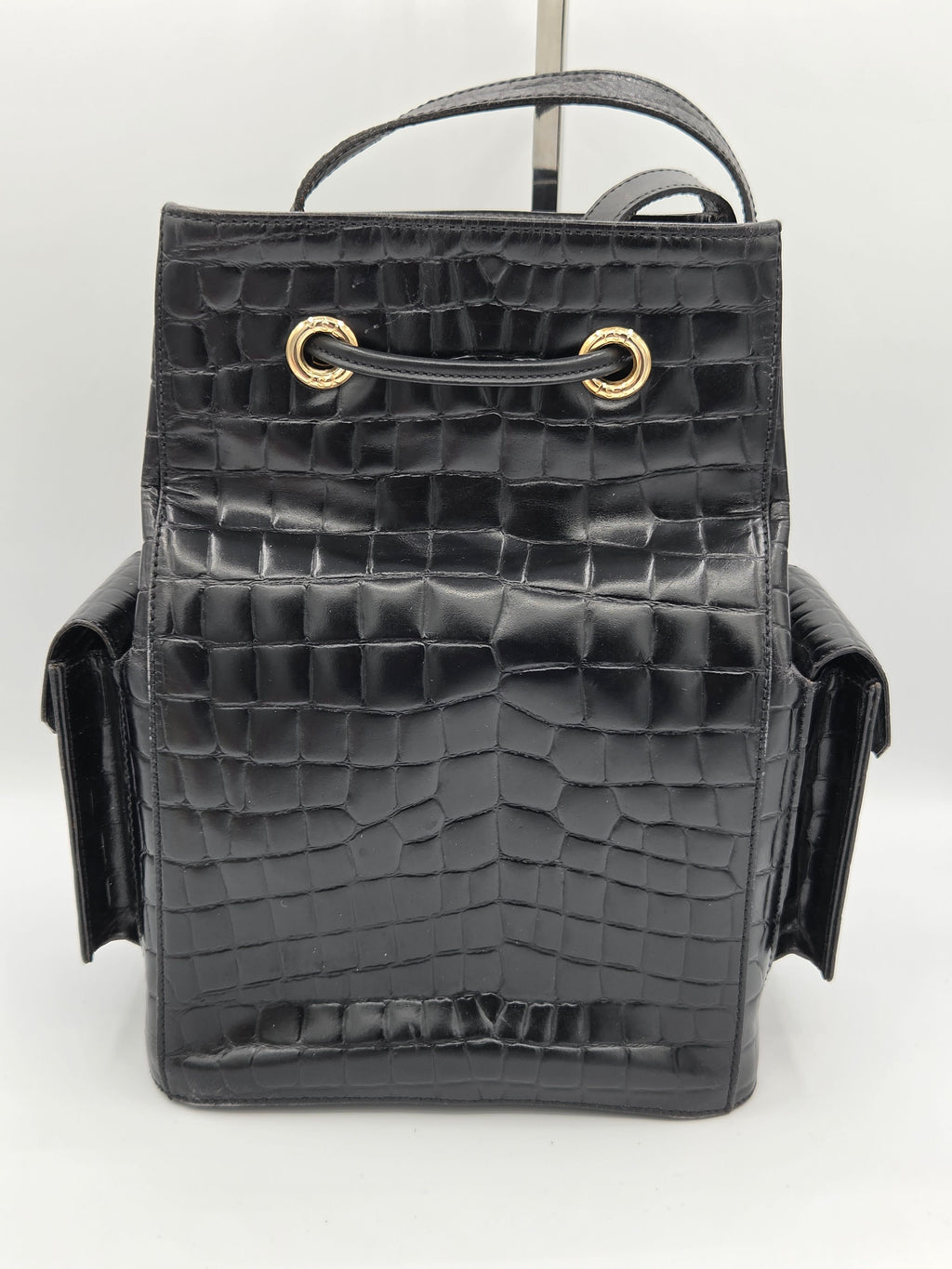 Black crocodile-patterned handbag with gold clasp on a white background