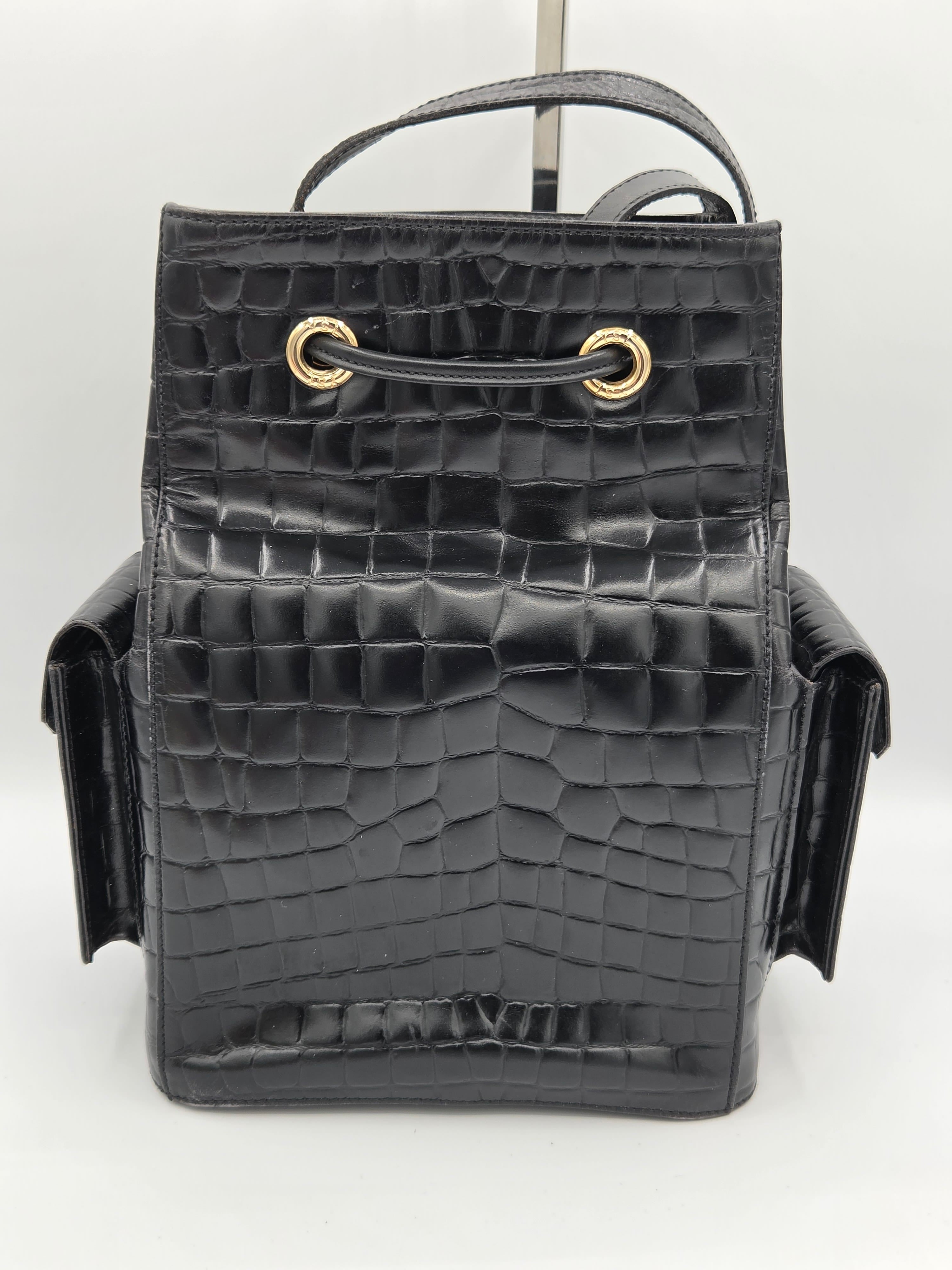 Black crocodile-patterned handbag with gold clasp on a white background