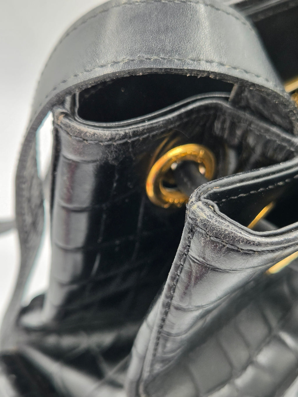 Close-up of a black leather handbag with gold clasp on a white background