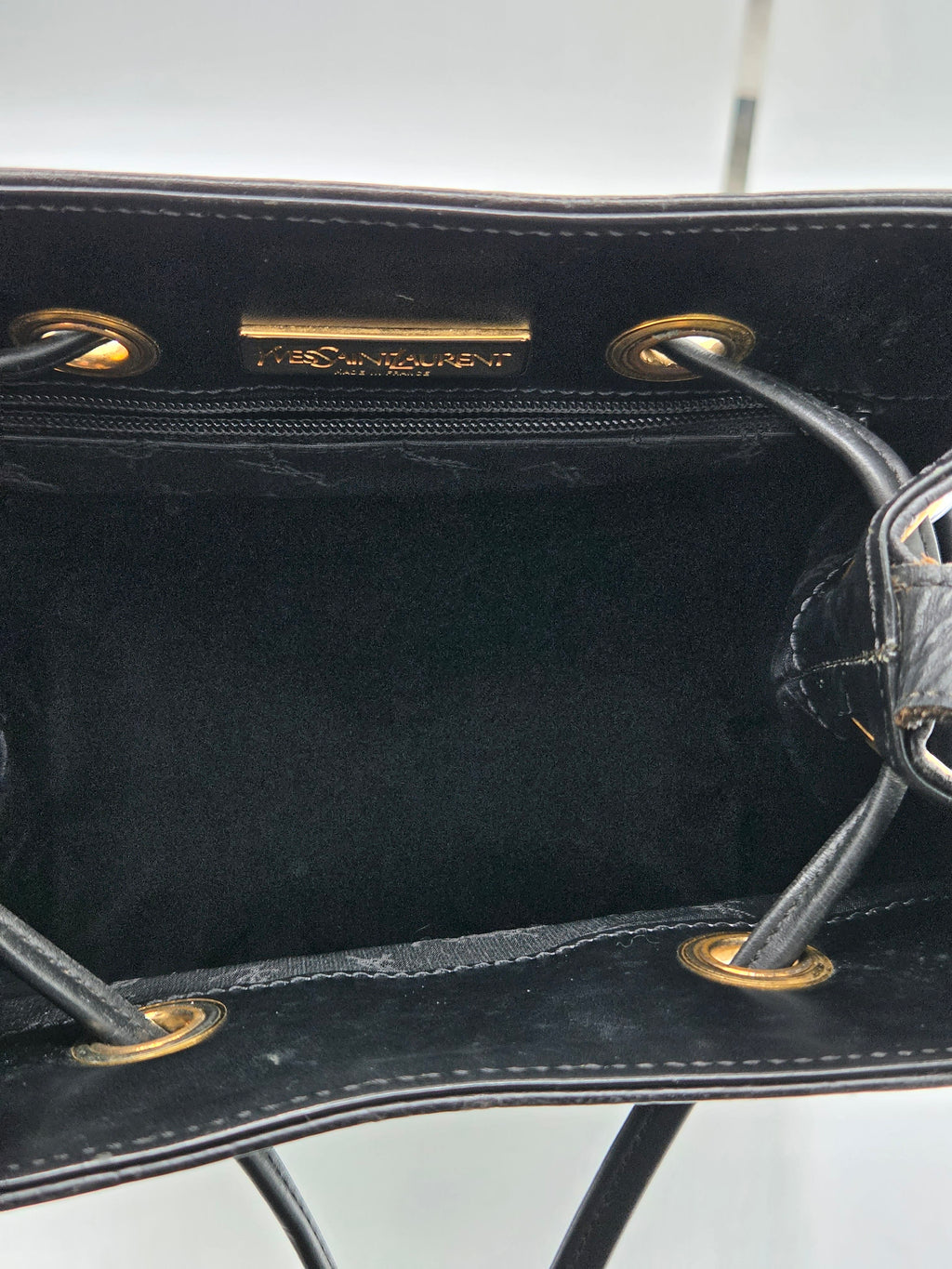 Close-up of a black handbag with gold hardware on a white background