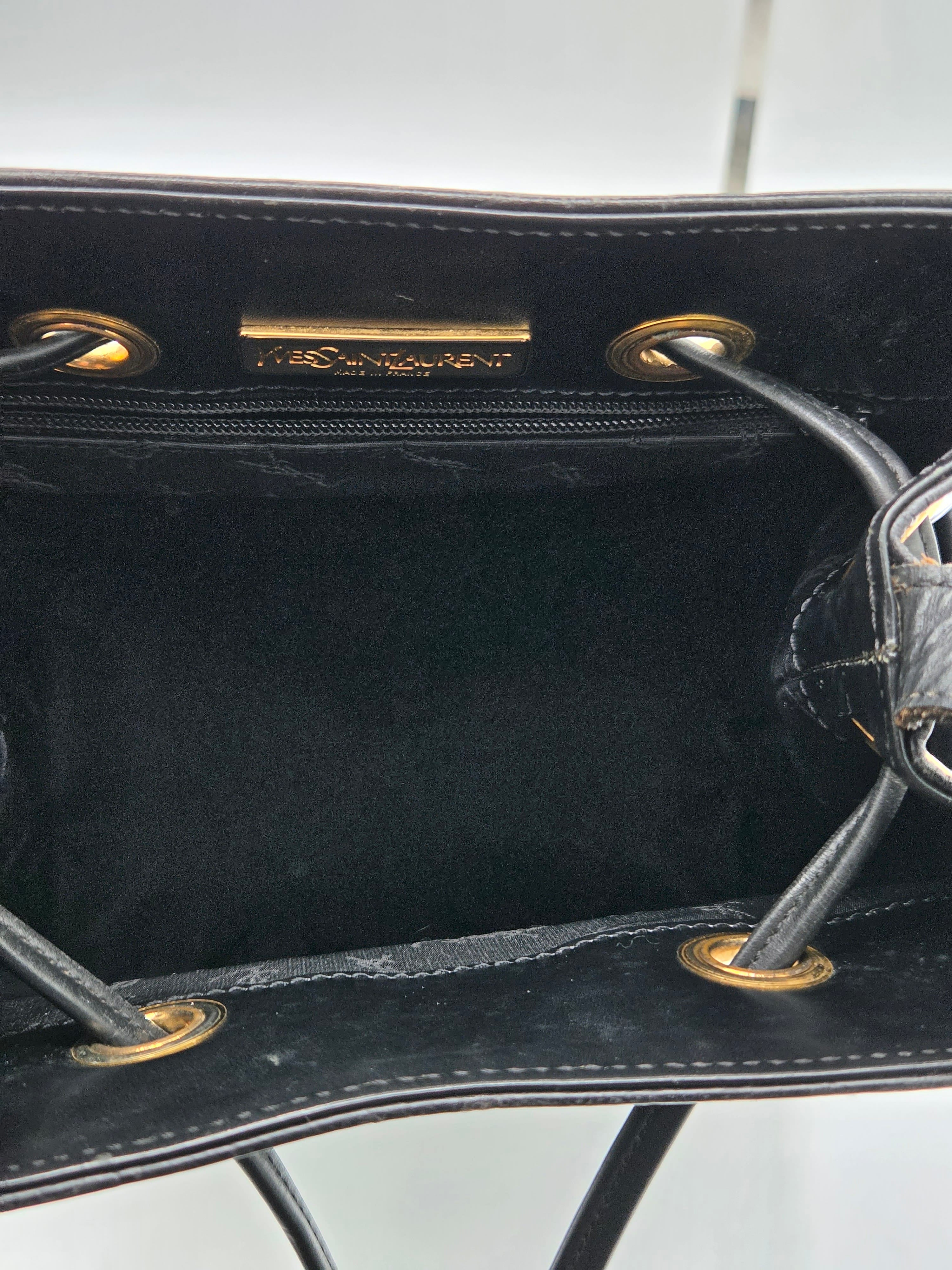Close-up of a black handbag with gold hardware on a white background