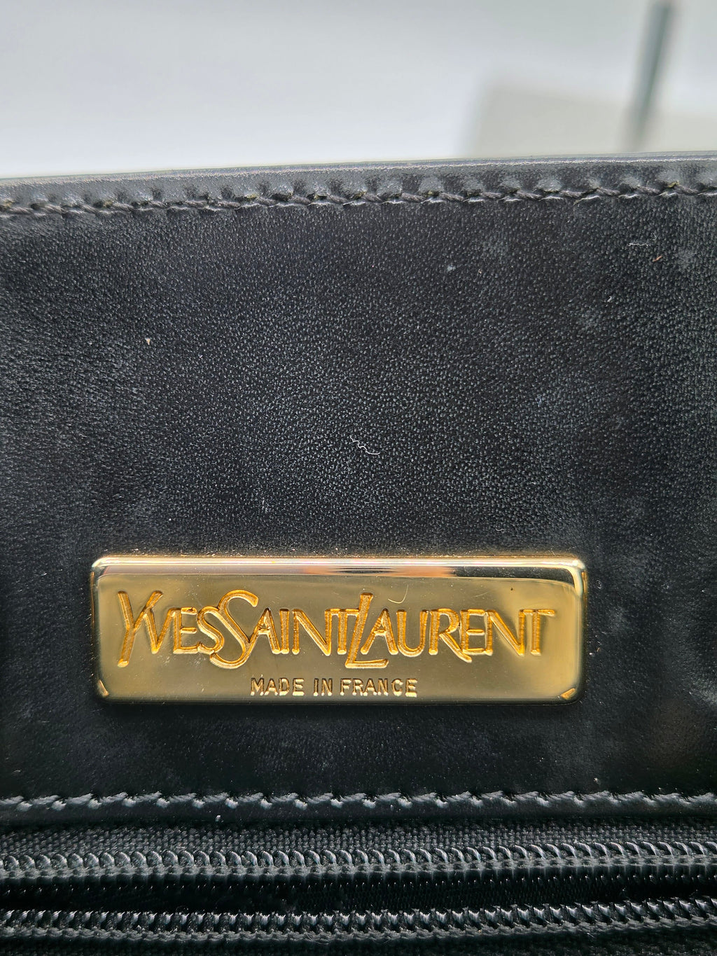 Black leather product with Yves Saint Laurent logo on a blurred background