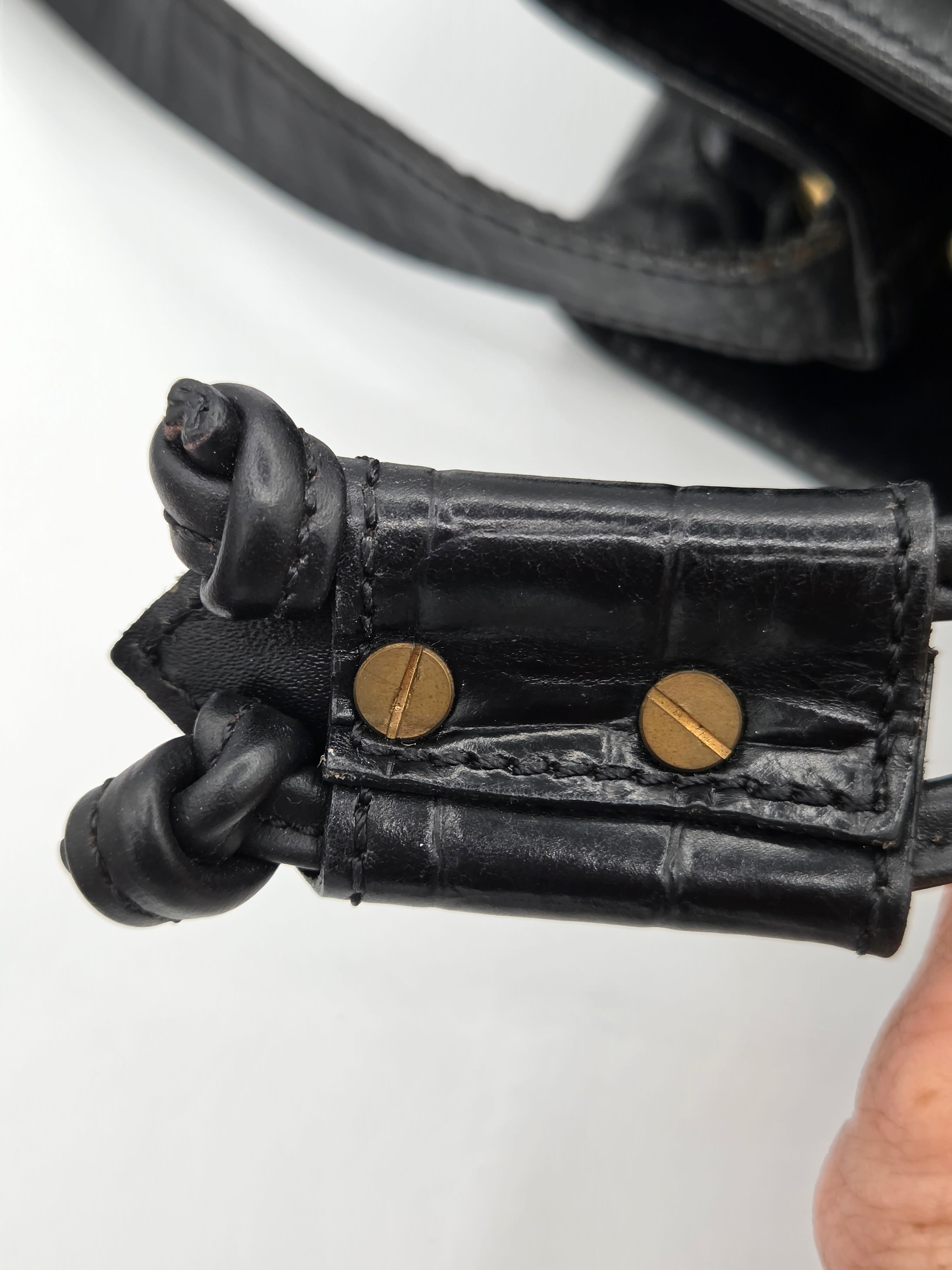 Close-up of a black leather glove with gold buttons on a white background