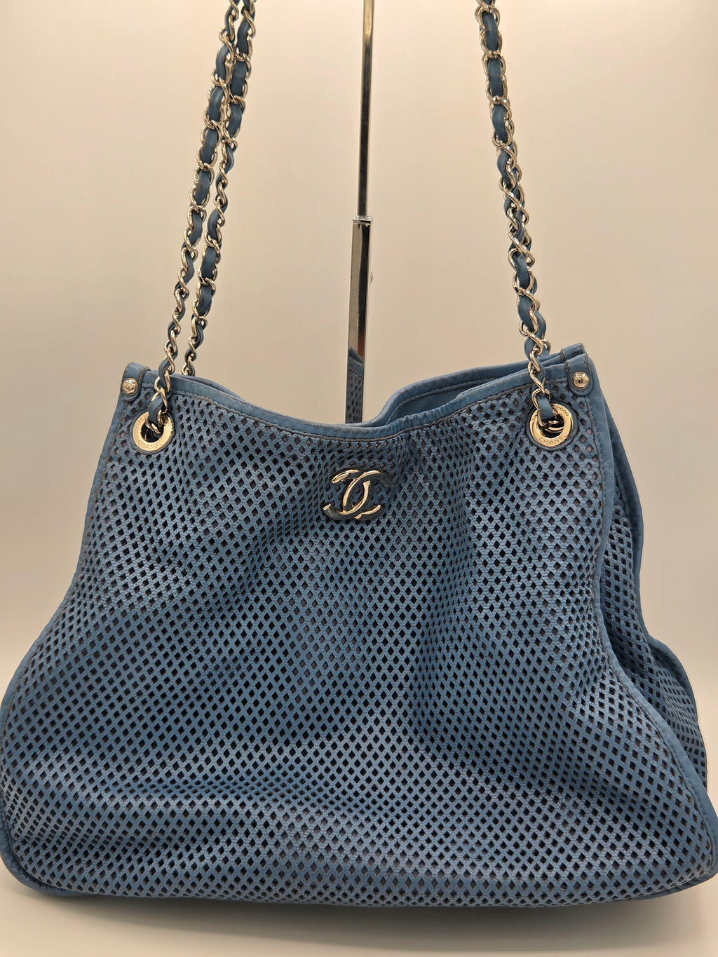 Blue handbag with gold chain strap on a beige background