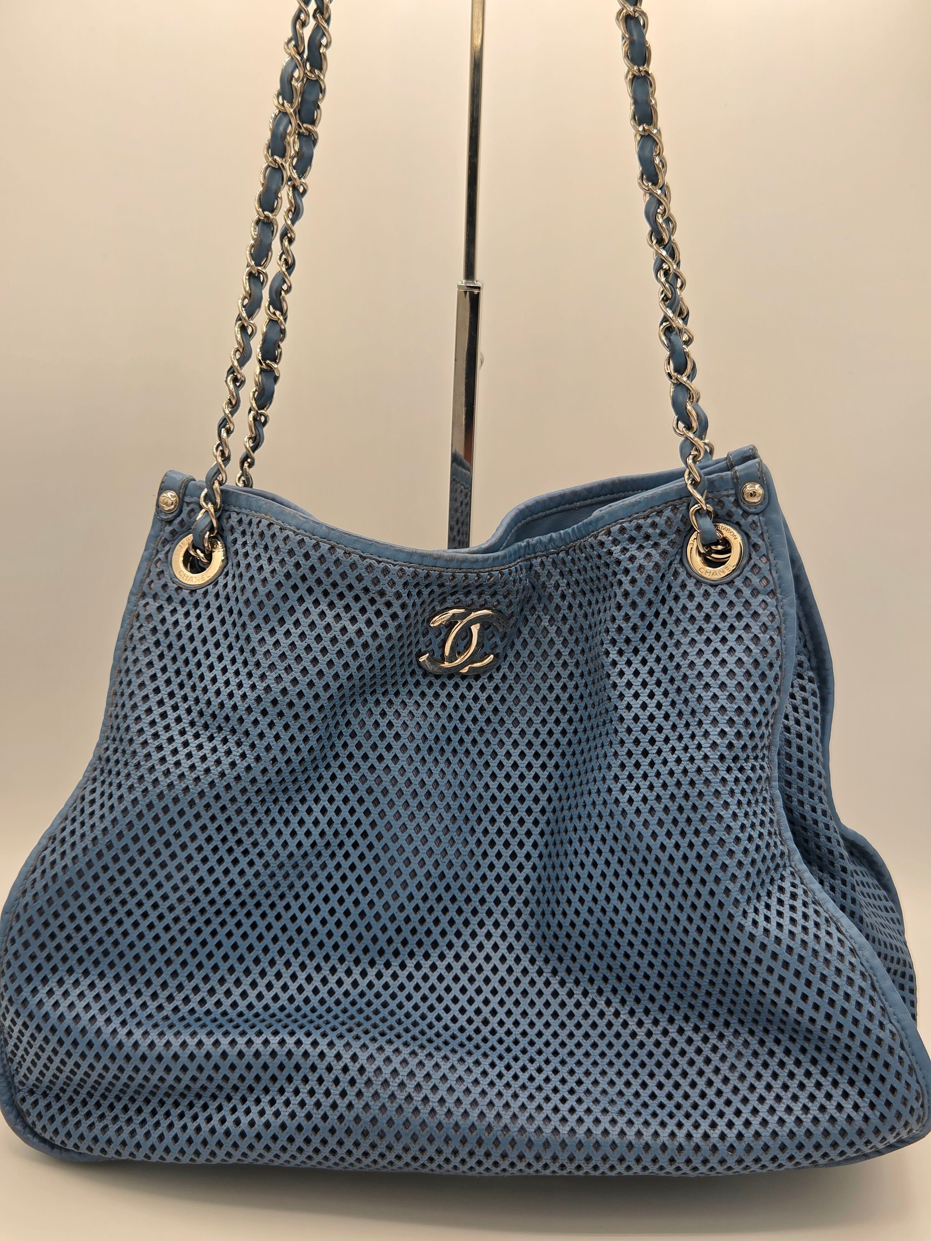 Blue handbag with gold chain strap on a beige background