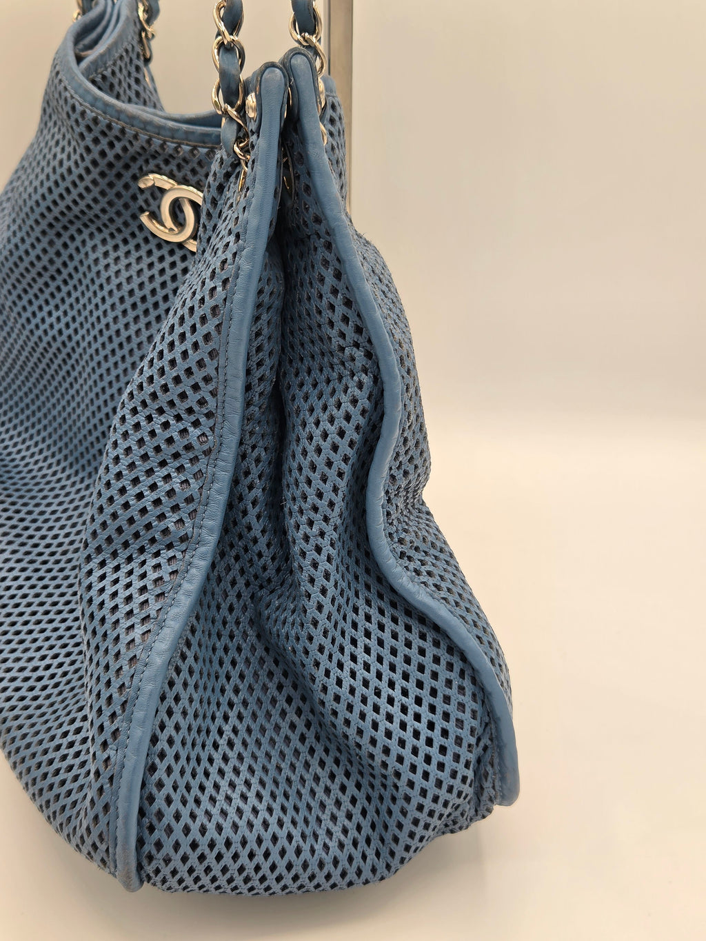 Blue textured handbag with a gold chain on a light background