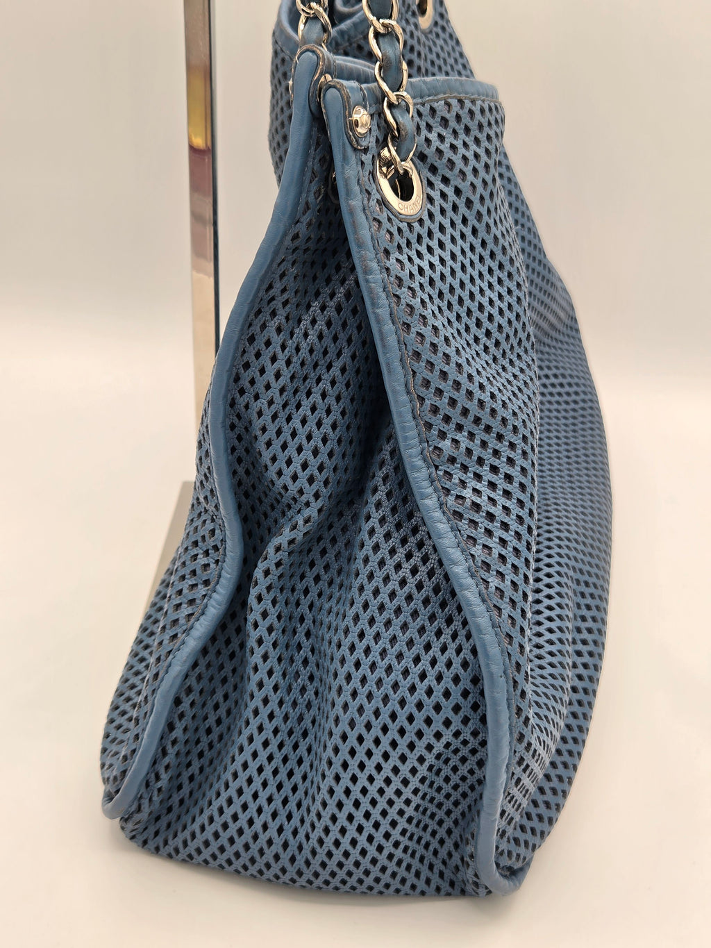 Blue mesh bag with gold chain on a light gray background