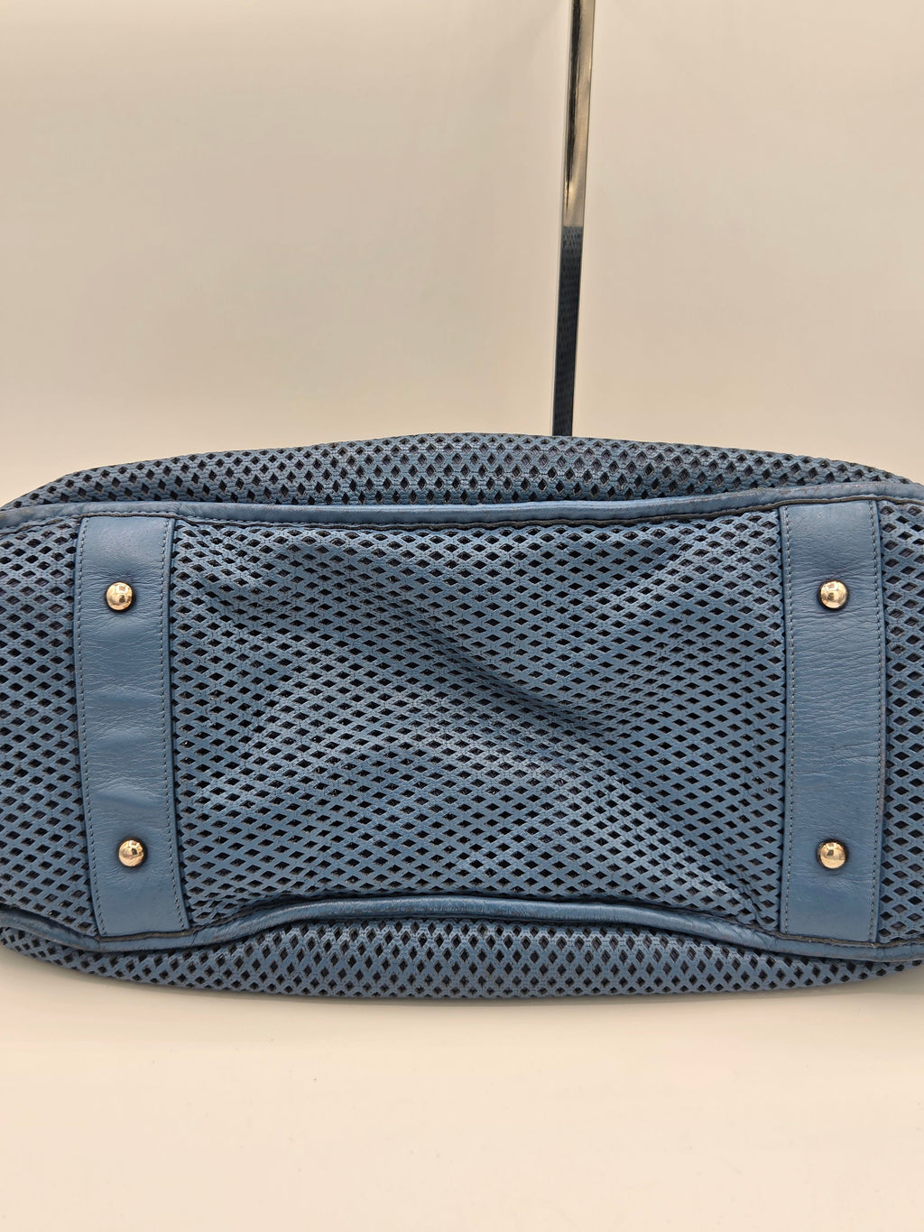 Blue mesh pouch with leather accents on a beige background