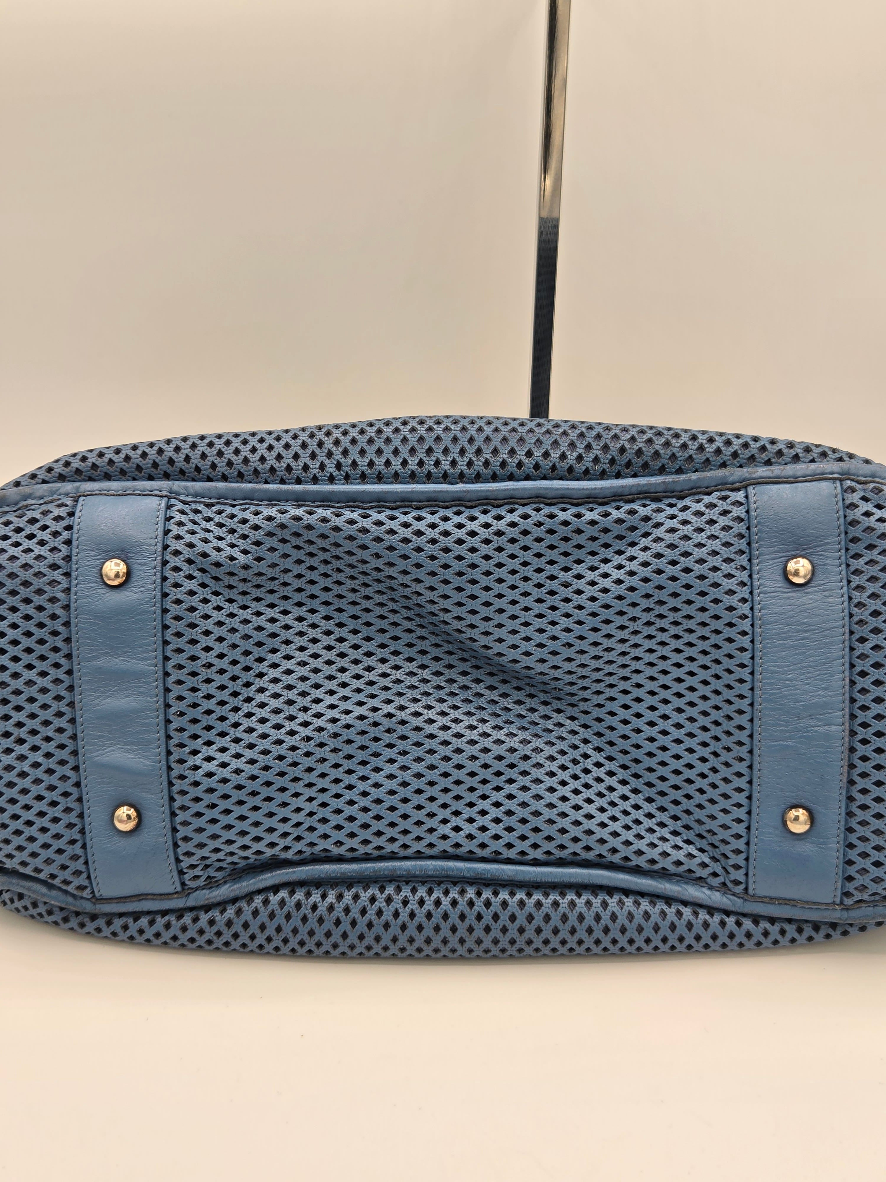 Blue mesh pouch with leather accents on a beige background