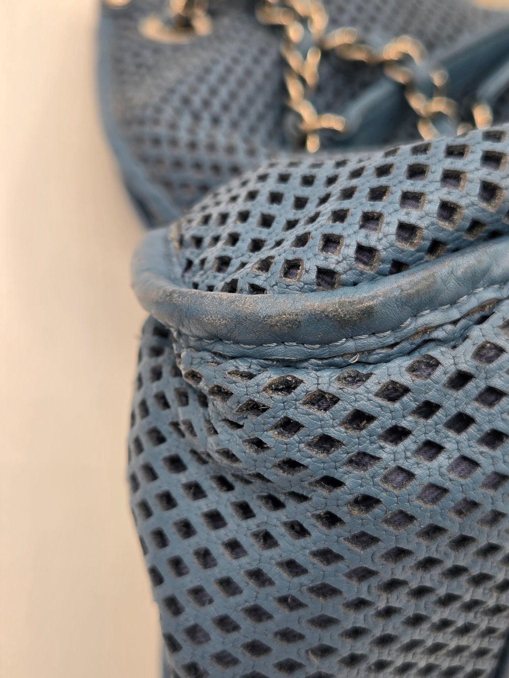 Close-up of a textured blue fabric with a chain detail on a beige background