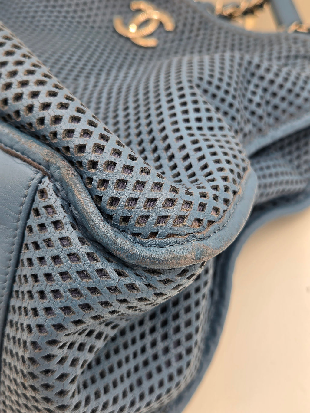 Close-up of a textured blue handbag with a gold logo.