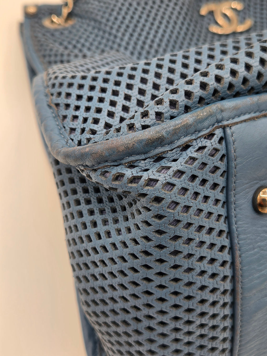Close-up of a blue textured handbag with gold hardware on a light background