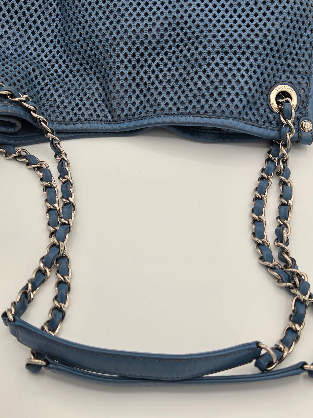 Blue handbag with chain strap on a light gray background