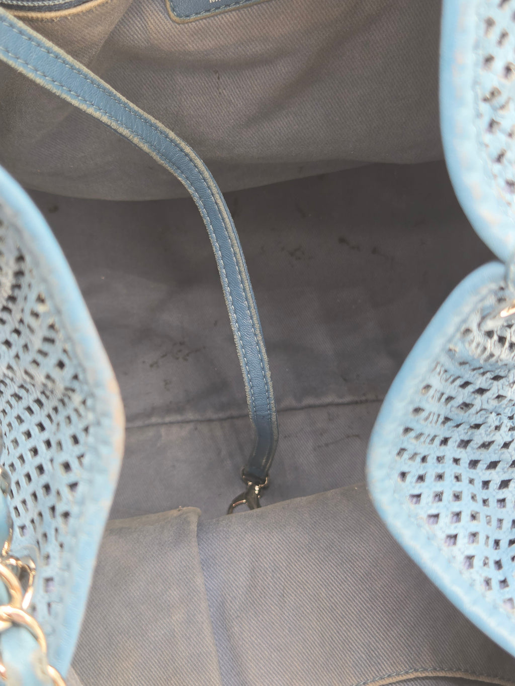 Close-up of a gray bag with a blue strap and textured top.