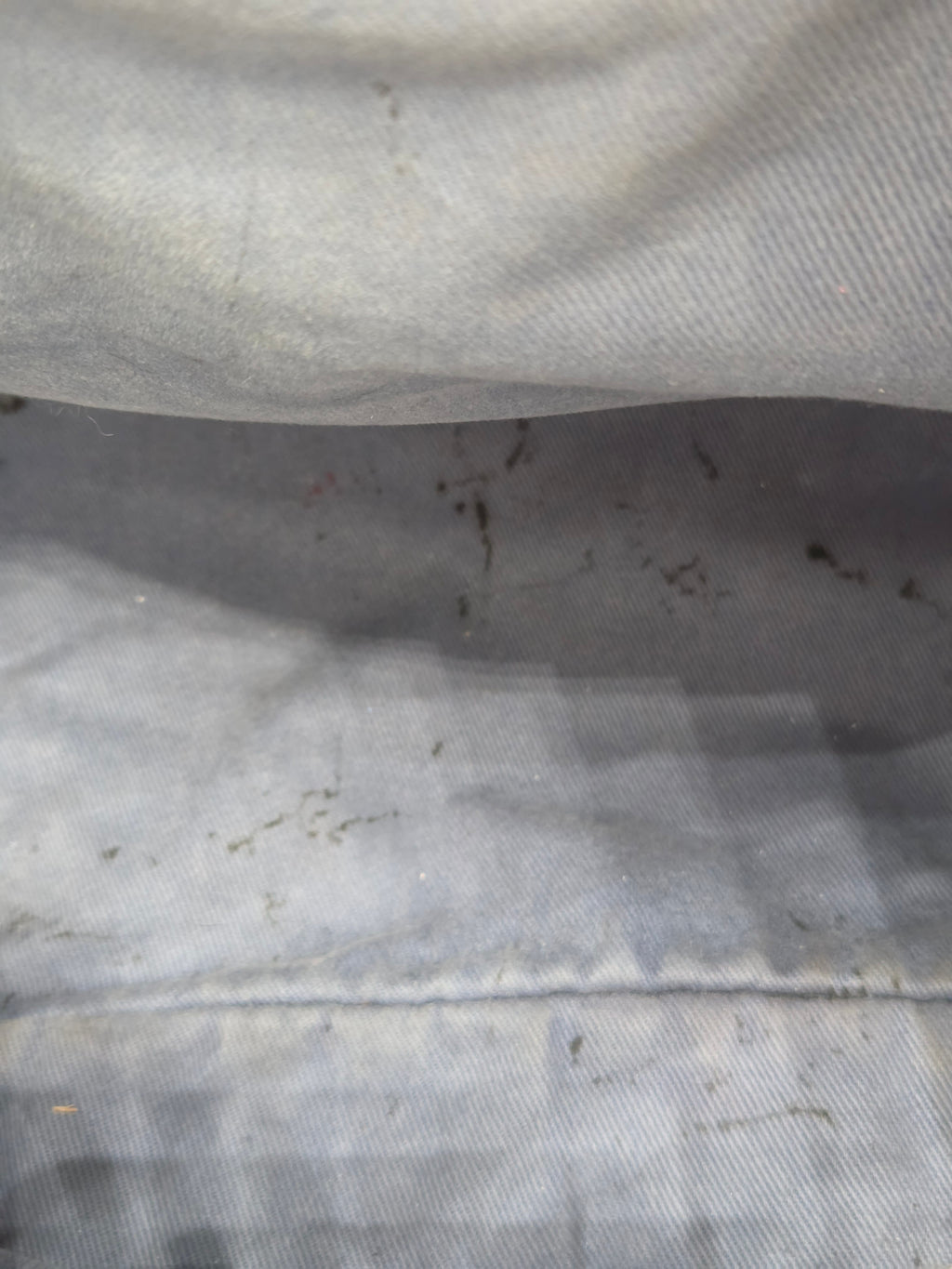 Close-up of a textured fabric surface with visible dirt and stains.