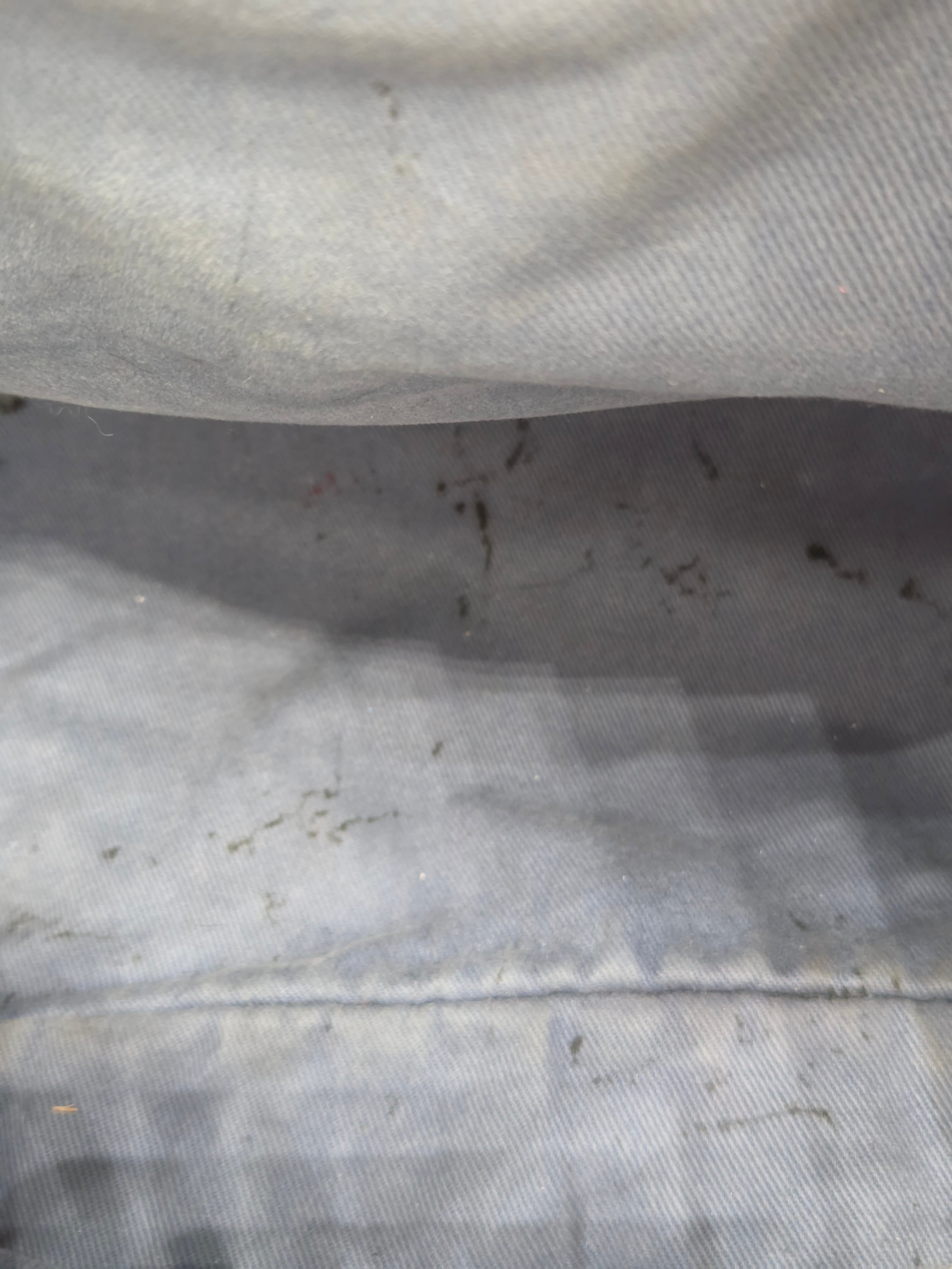 Close-up of a textured fabric surface with visible dirt and stains.