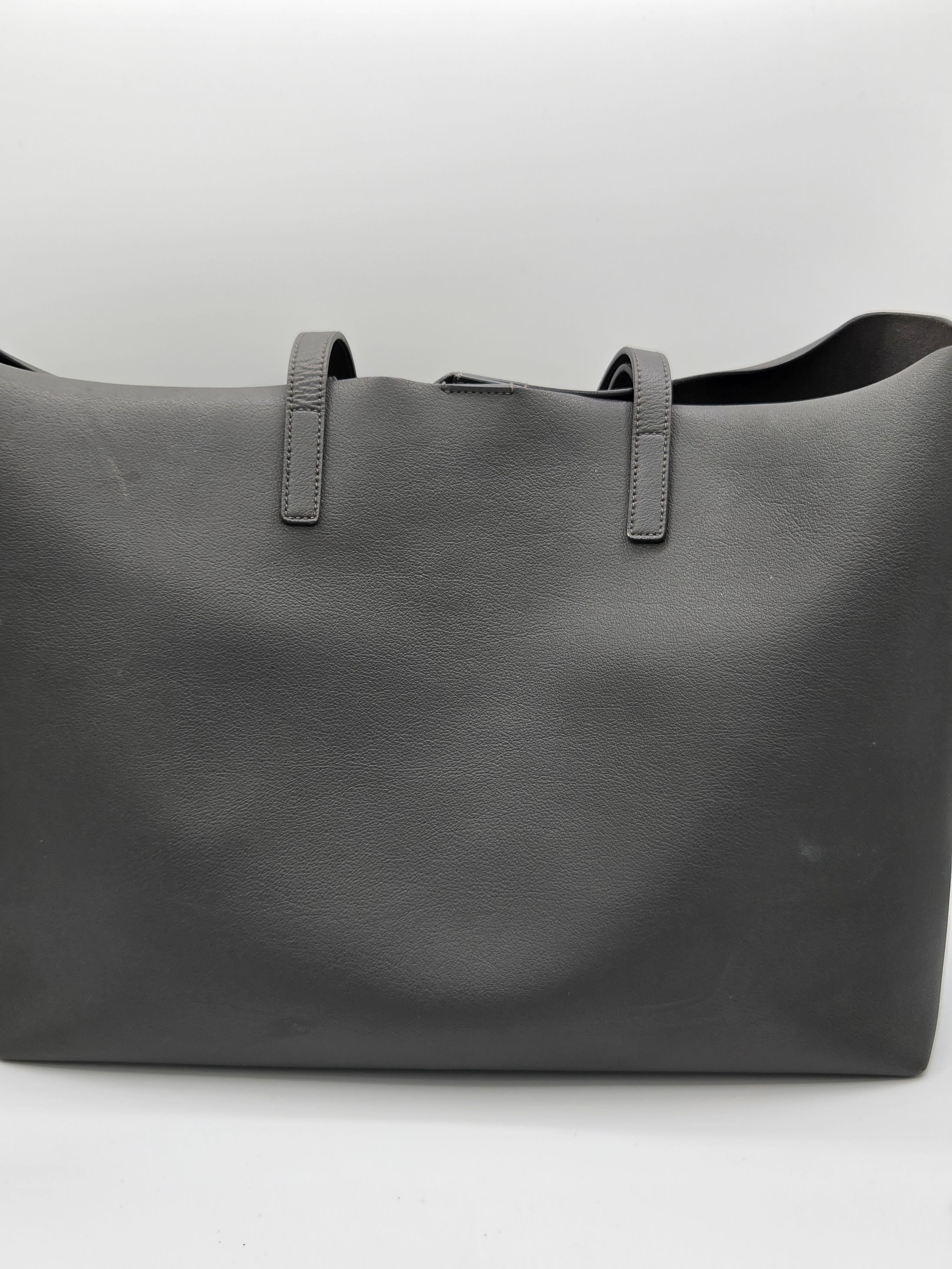 Dark gray leather bag with visible stitching on a light gray background