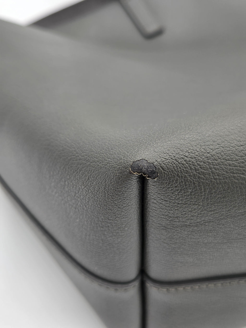 Close-up of a small hole in gray leather upholstery